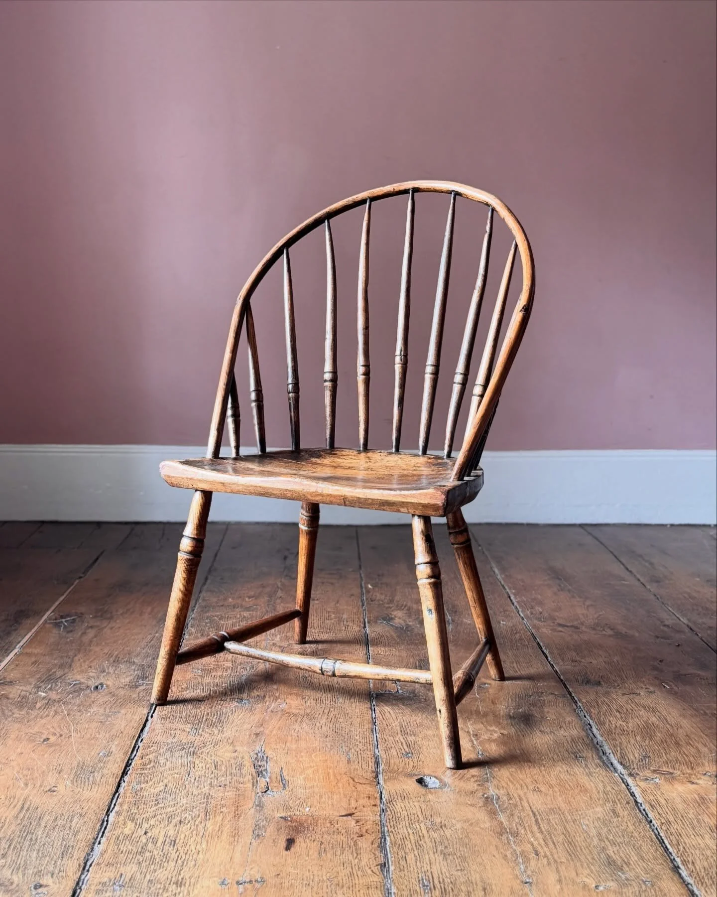 An early 19th Century hoop back Windsor chair in elm and ash with remnants of the original green paint. A quirky and attractive primitive shape, on turned legs with a slab seat. Possibly had arms at some point but was adapted to its current shape sho