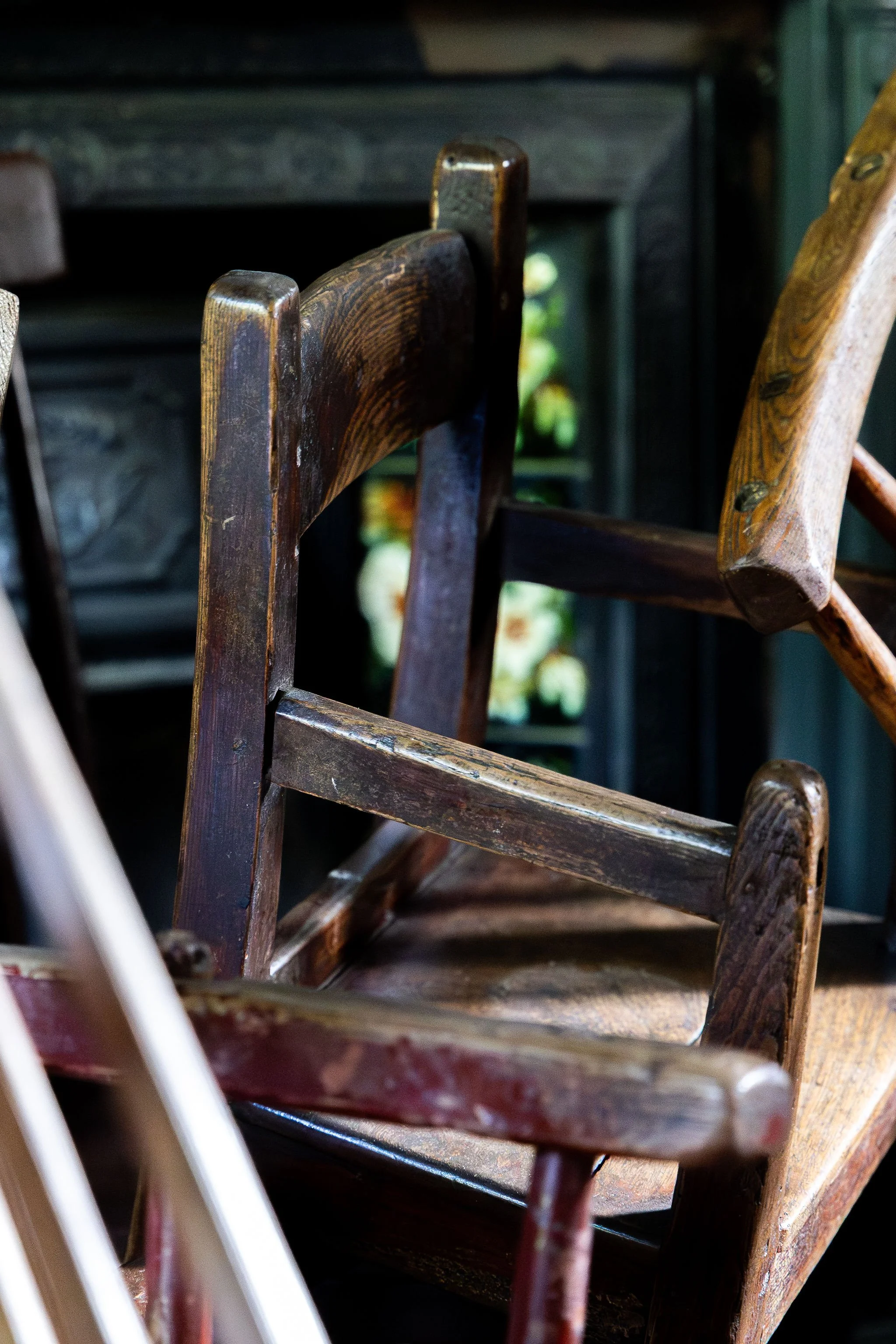 Close-up of vintage wooden chairs stacked or leaning against each other indoors with natural light.