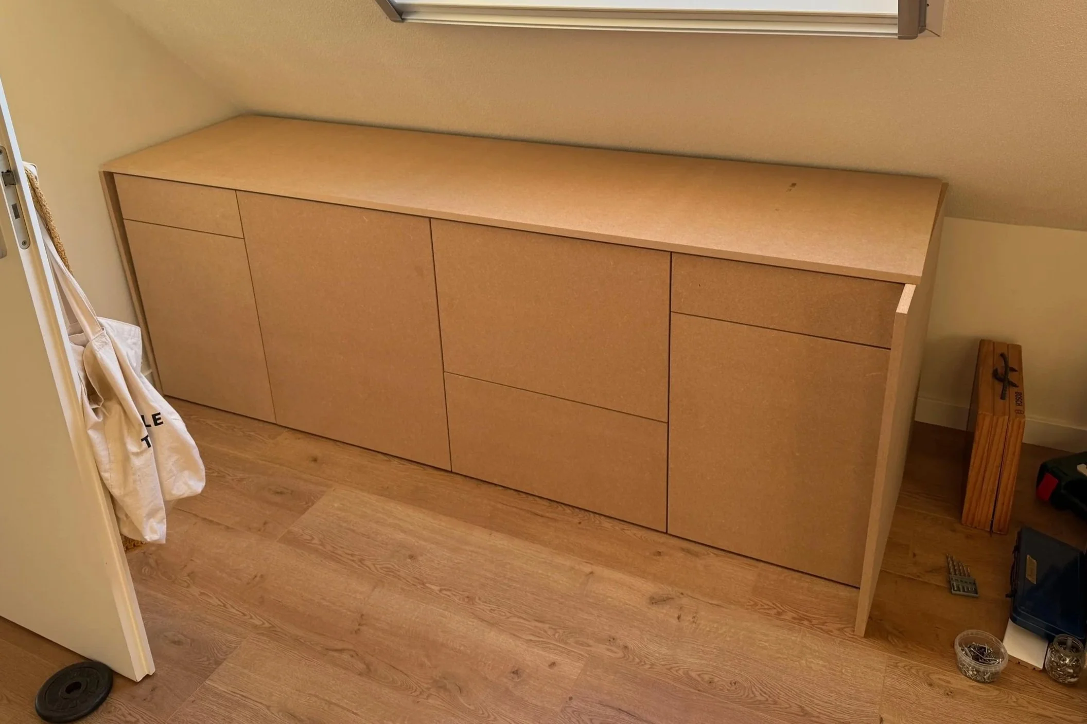 Een houten dressoir met vier kastdeuren in een kamer met houten vloer.