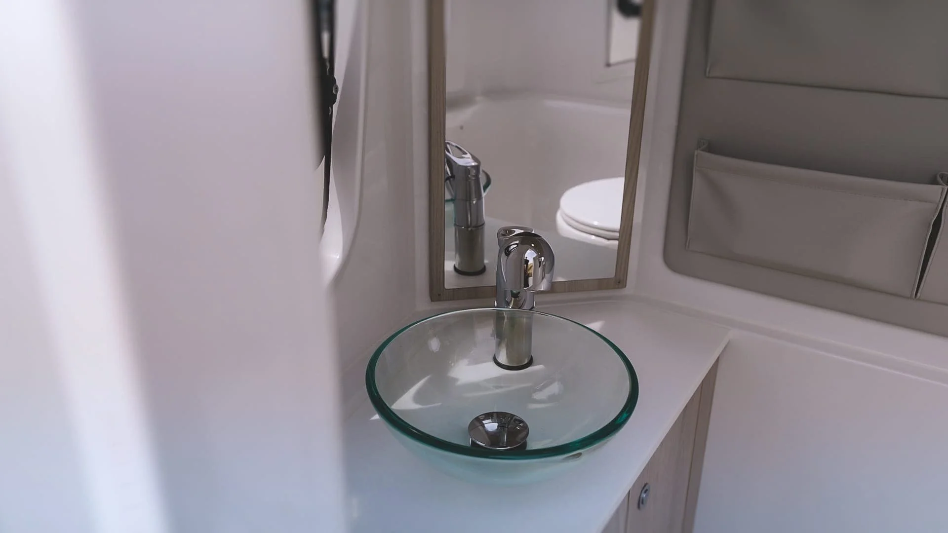 Small bathroom sink with a round glass basin, chrome faucet, mirror behind it, and wall-mounted organizer on the right. Sterk 31 Supersport