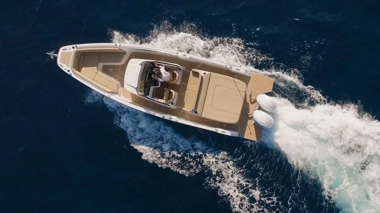 Overhead view of a motorboat speeding through dark blue water, creating white waves behind it. Sterk 31RC overhead