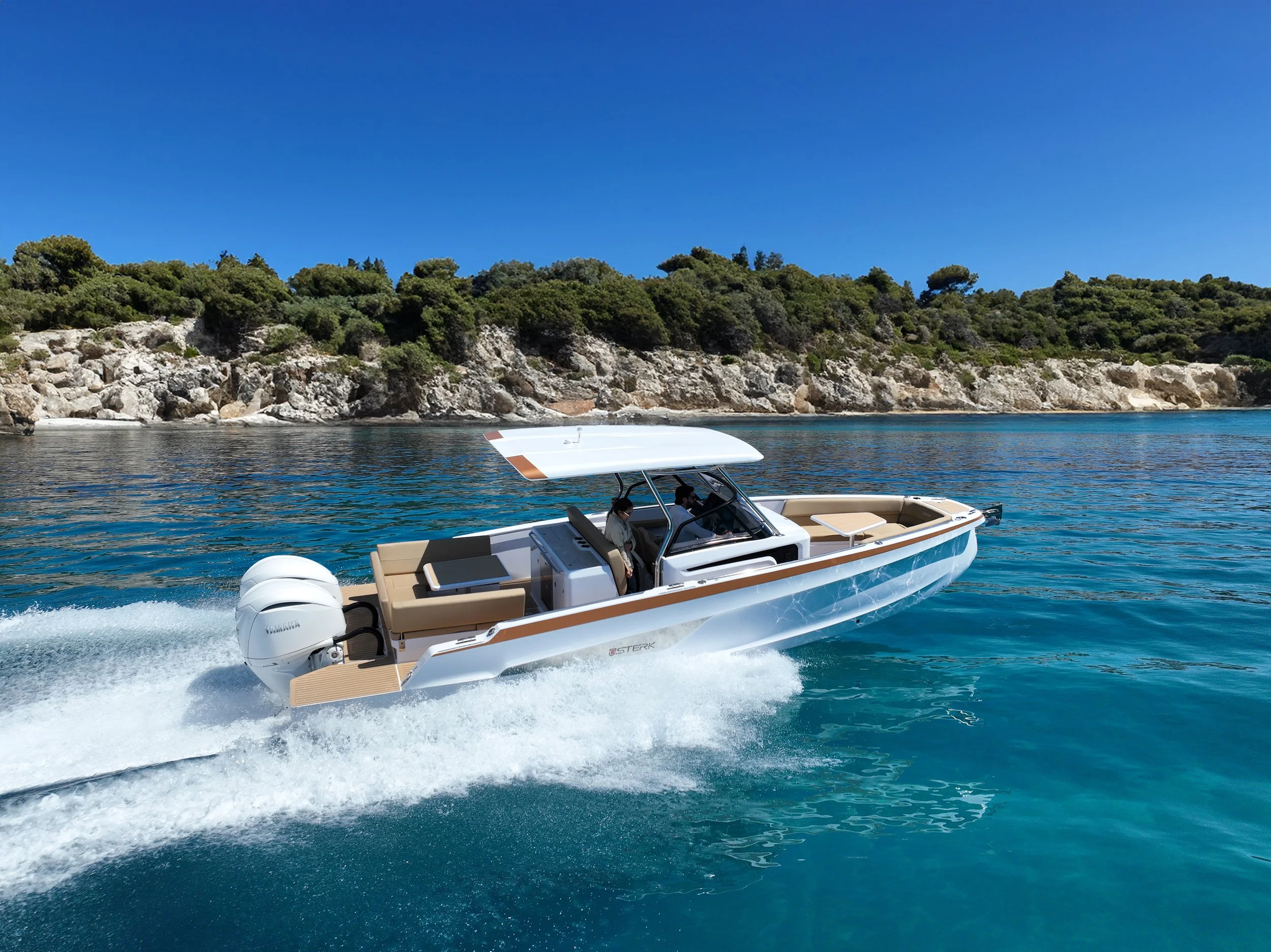 A white boat with beige seating and a white canopy moving through clear blue water near a rocky shoreline with green trees under a bright blue sky.