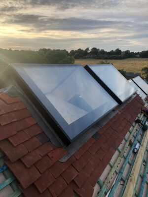 Solar roof windows installed on a tiled roof, with an outdoor landscape and cloudy sky in the background.