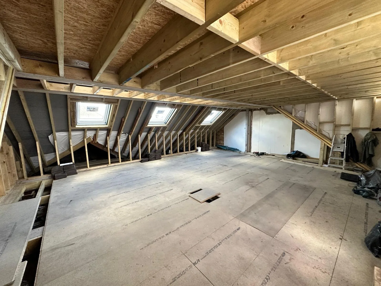 Attic under construction with exposed wooden framing, insulation, and skylights.