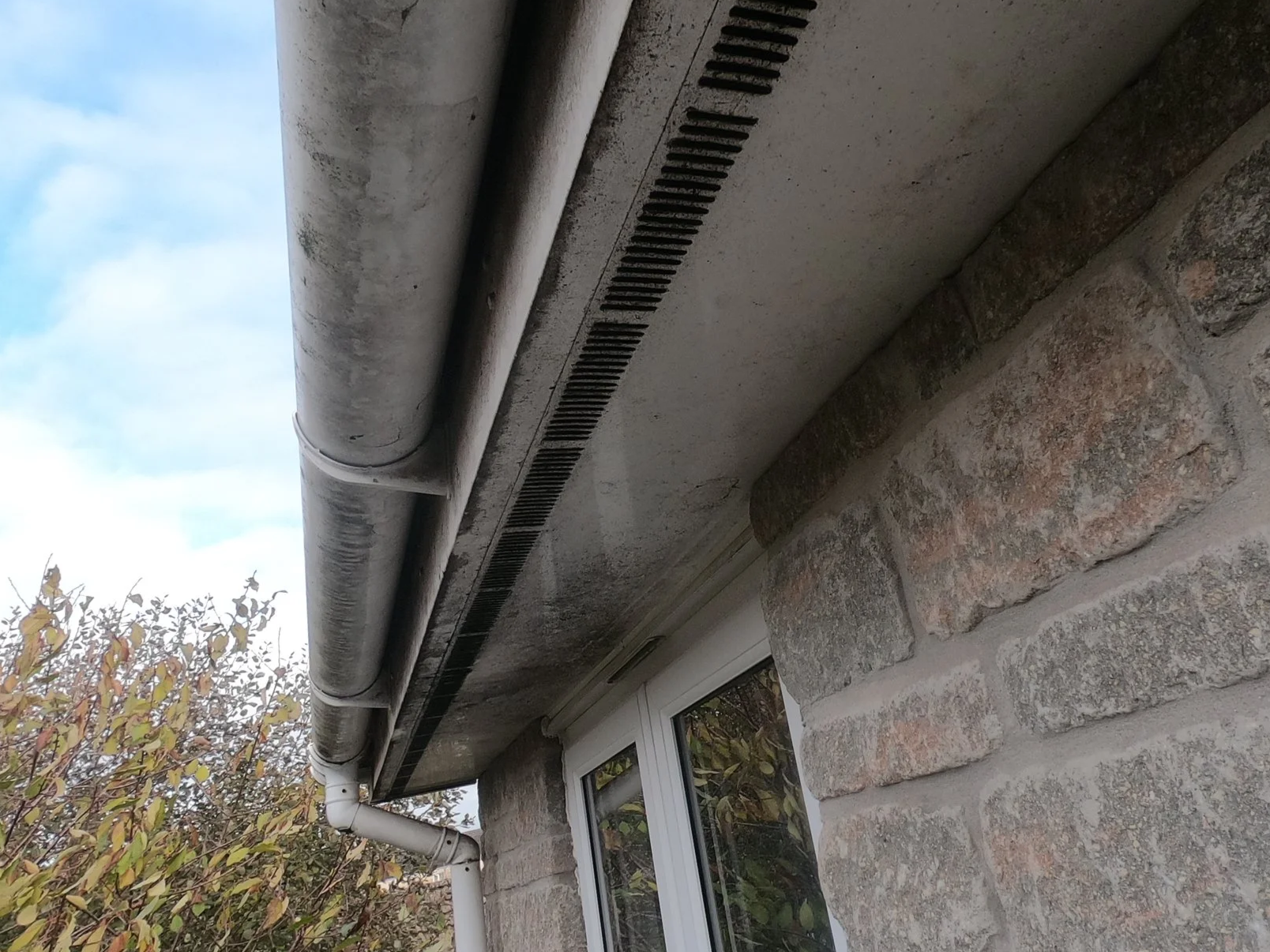 Before picture showing a dirty gutter and soffit.