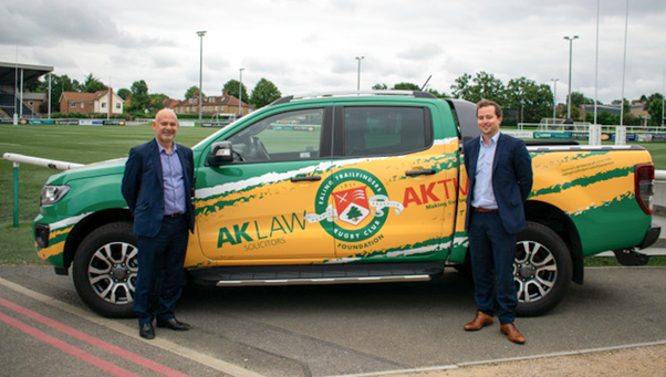 Two partnera at AK Law standing next to a green pickup truck the 'Aktivator’ for the AKLA Foundation.