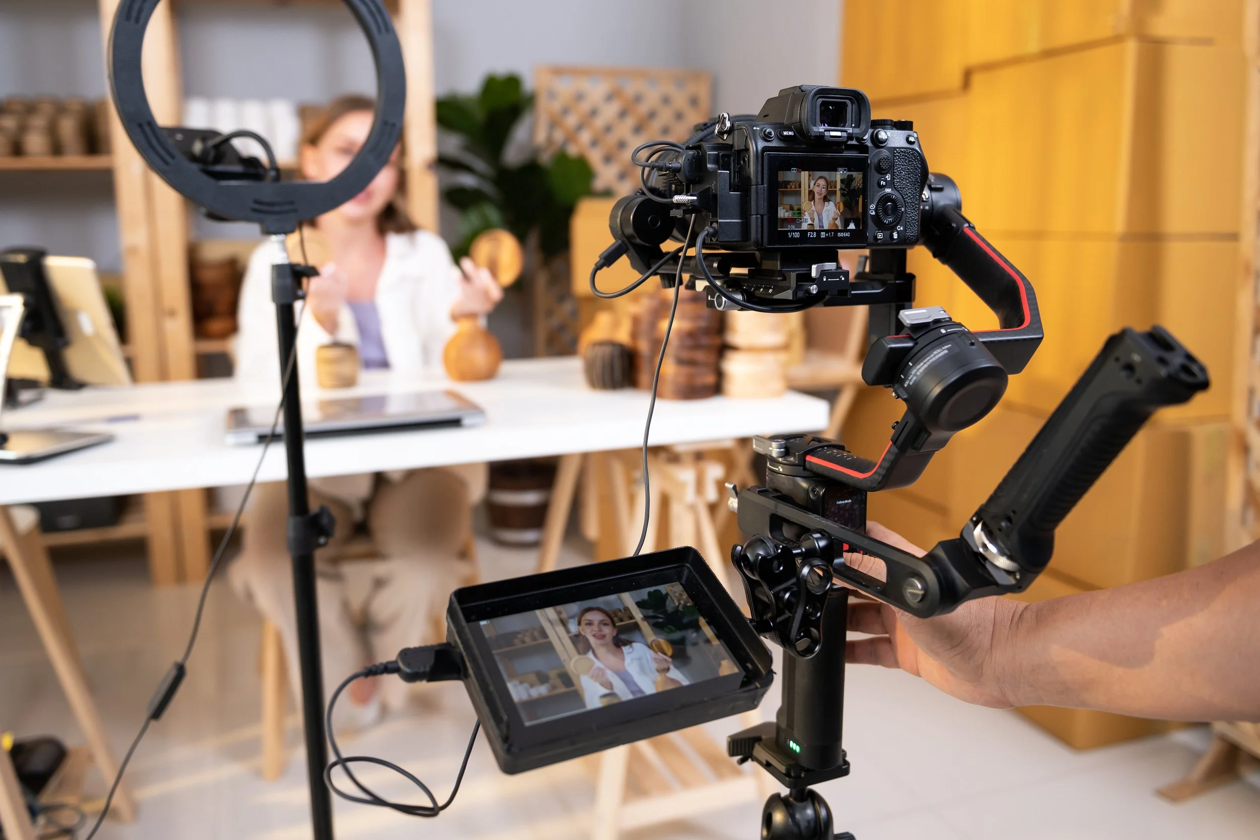 A studio setting with filming equipment including a camera on a stabilizer, a monitor, and lighting.