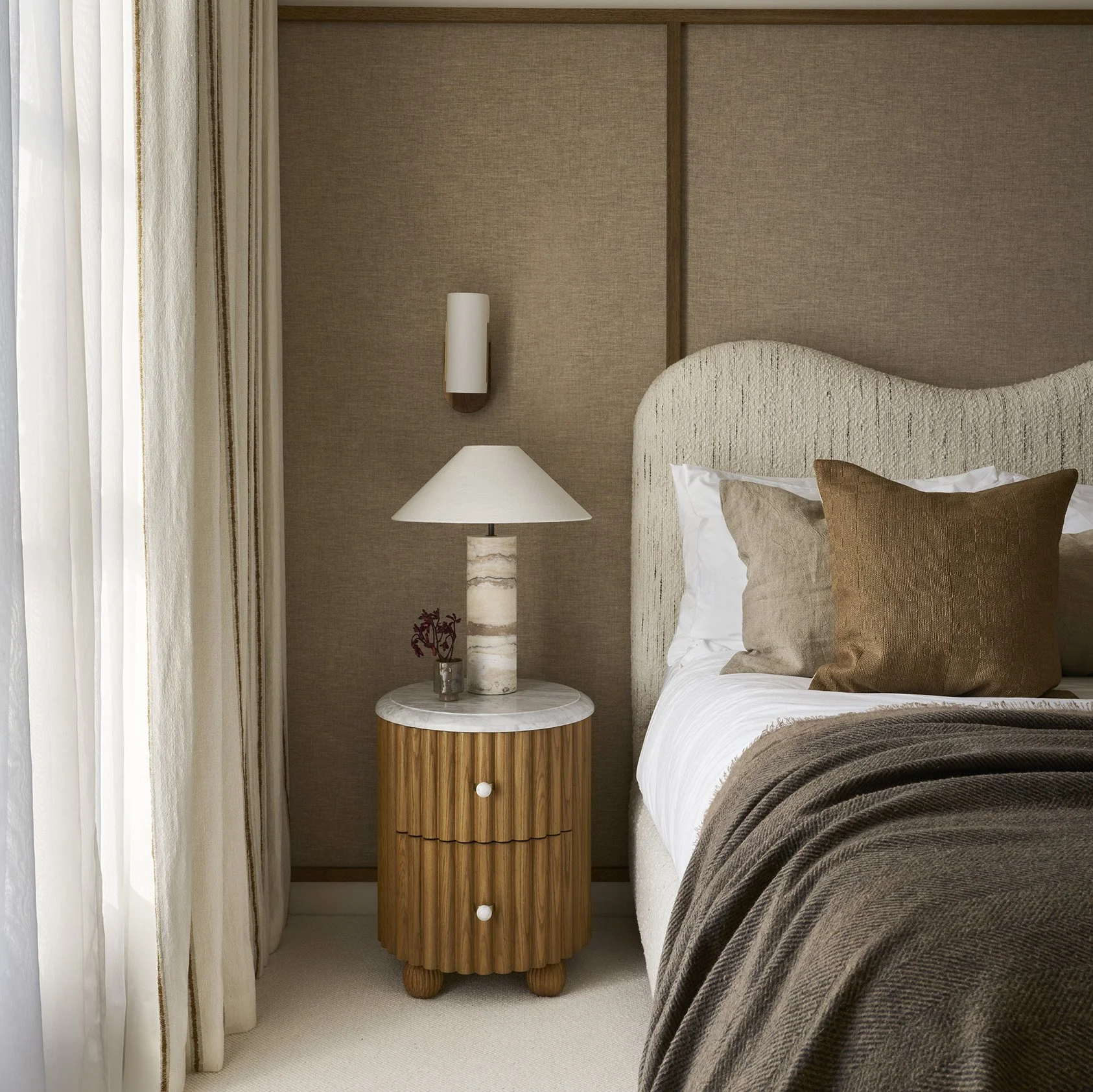 A bedroom scene with a bed, pillows, and a bedside table with a lamp.