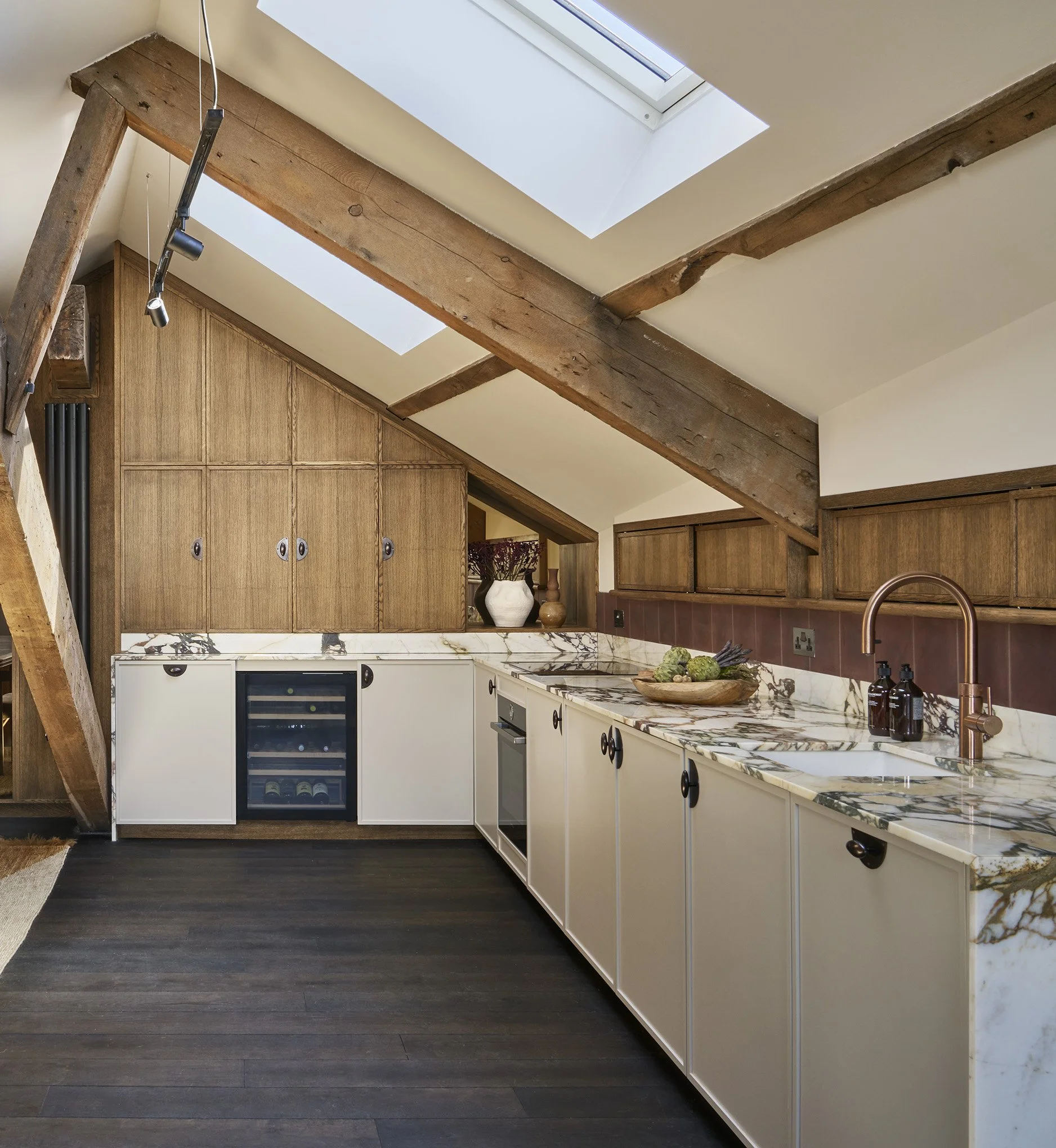Kitchen with wooden beams, skylights, marble countertop, white cabinets, and a small wine fridge.