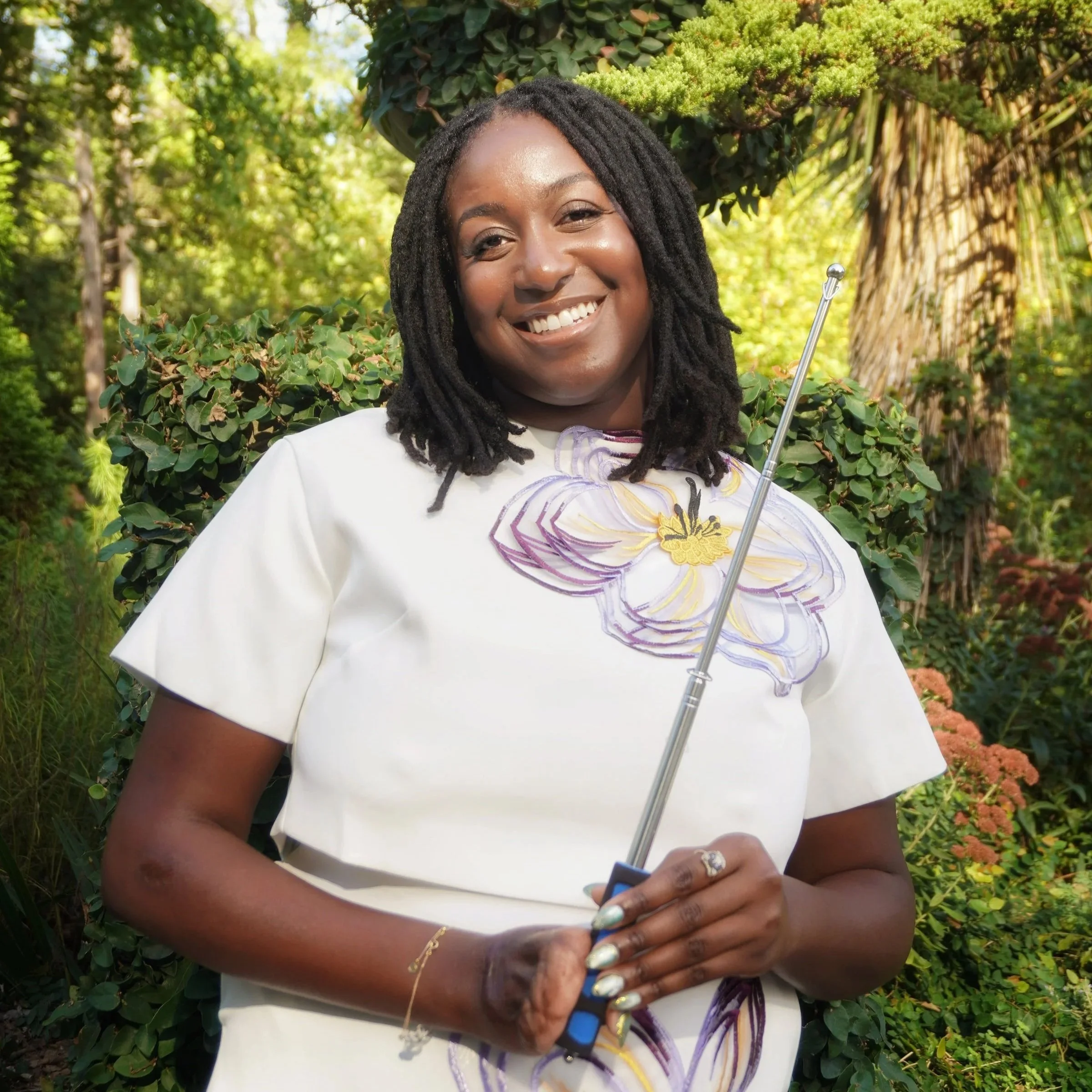 Raven Ransom smiling outdoors in nature setting wearing light colored outfit