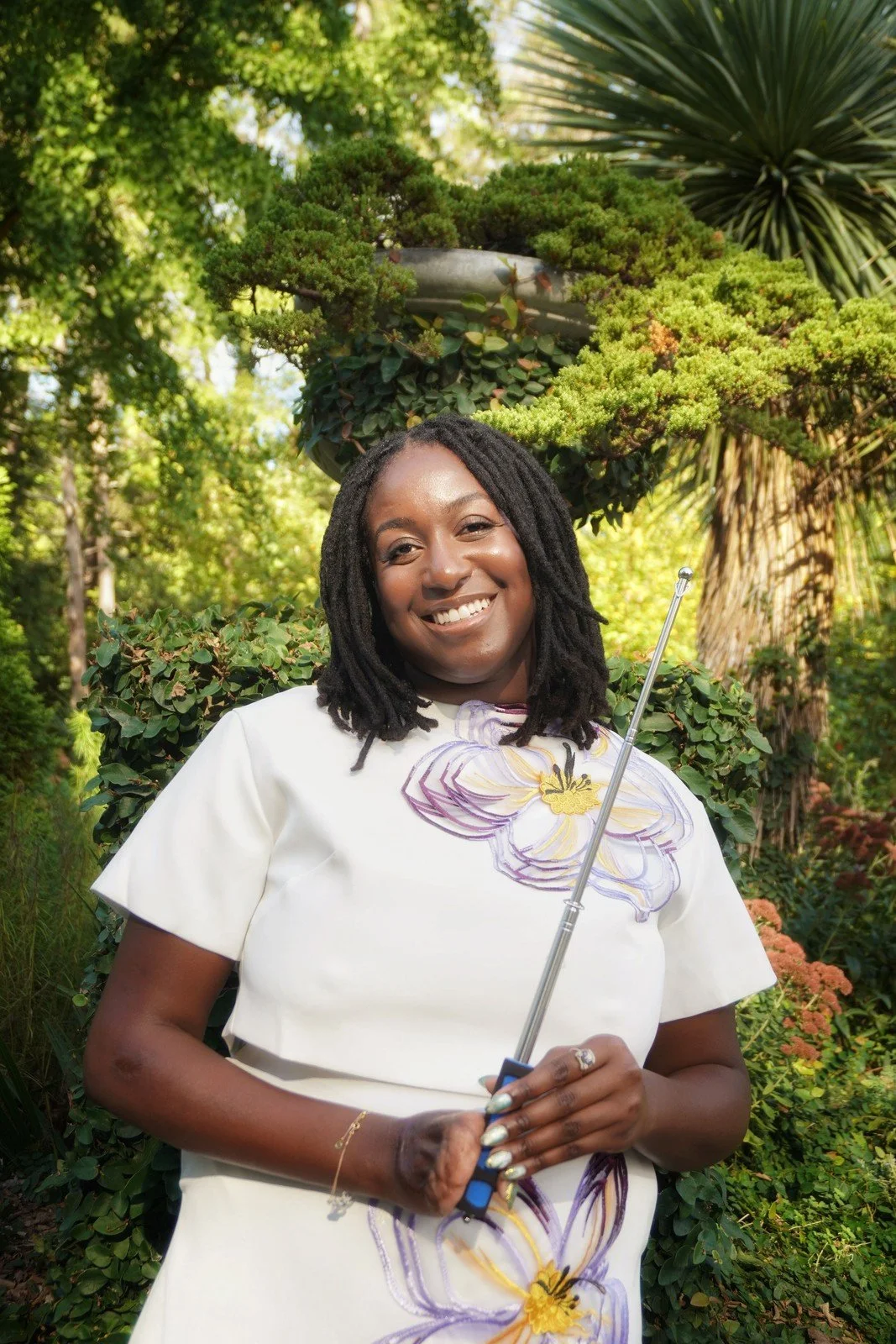 Raven Ransom smiling outdoors in nature setting wearing light colored outfit