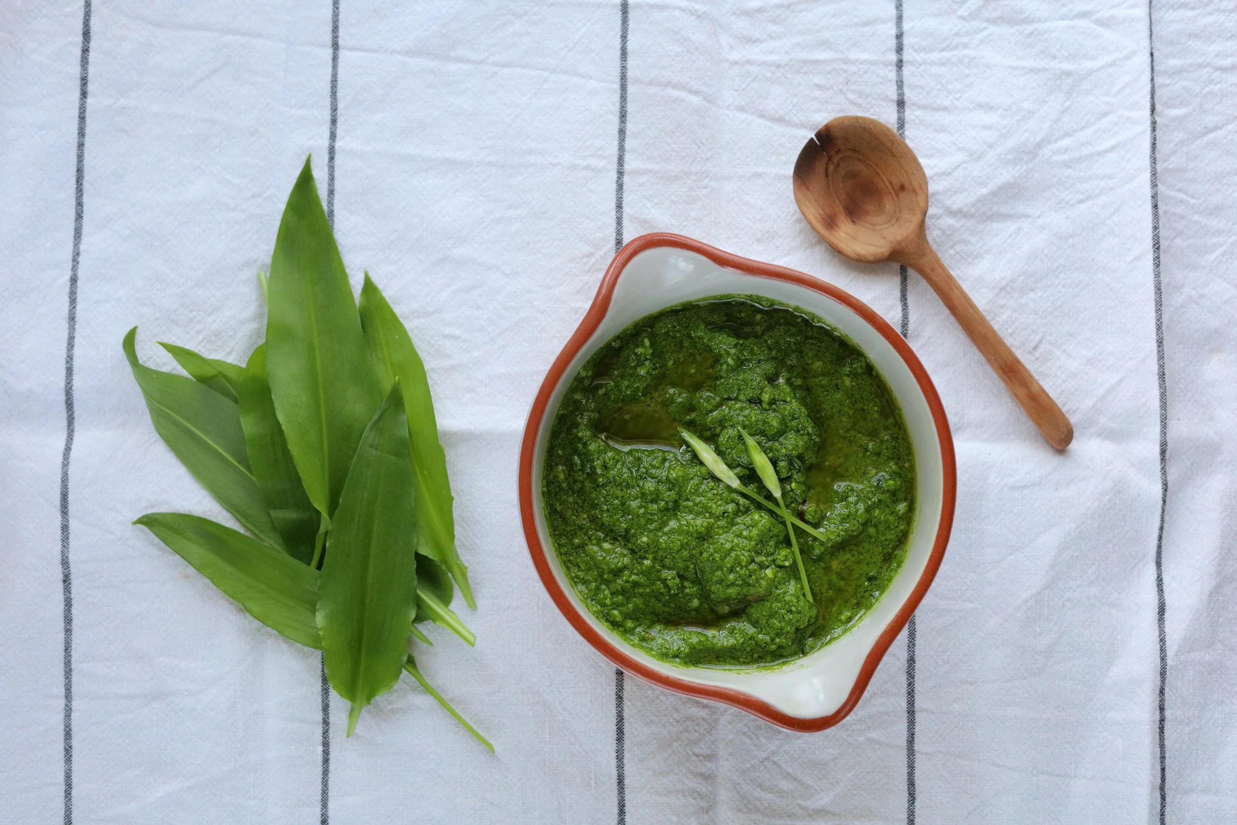wild garlic pesto with wild garlic leaves and wooden spoon