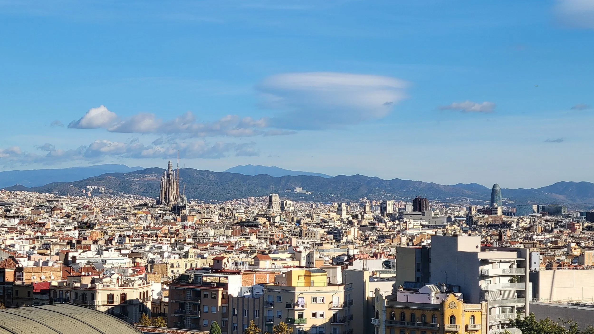 view of barcelona from montjuic with sagrada familia visible in the distance with rolling mountian hills in the background