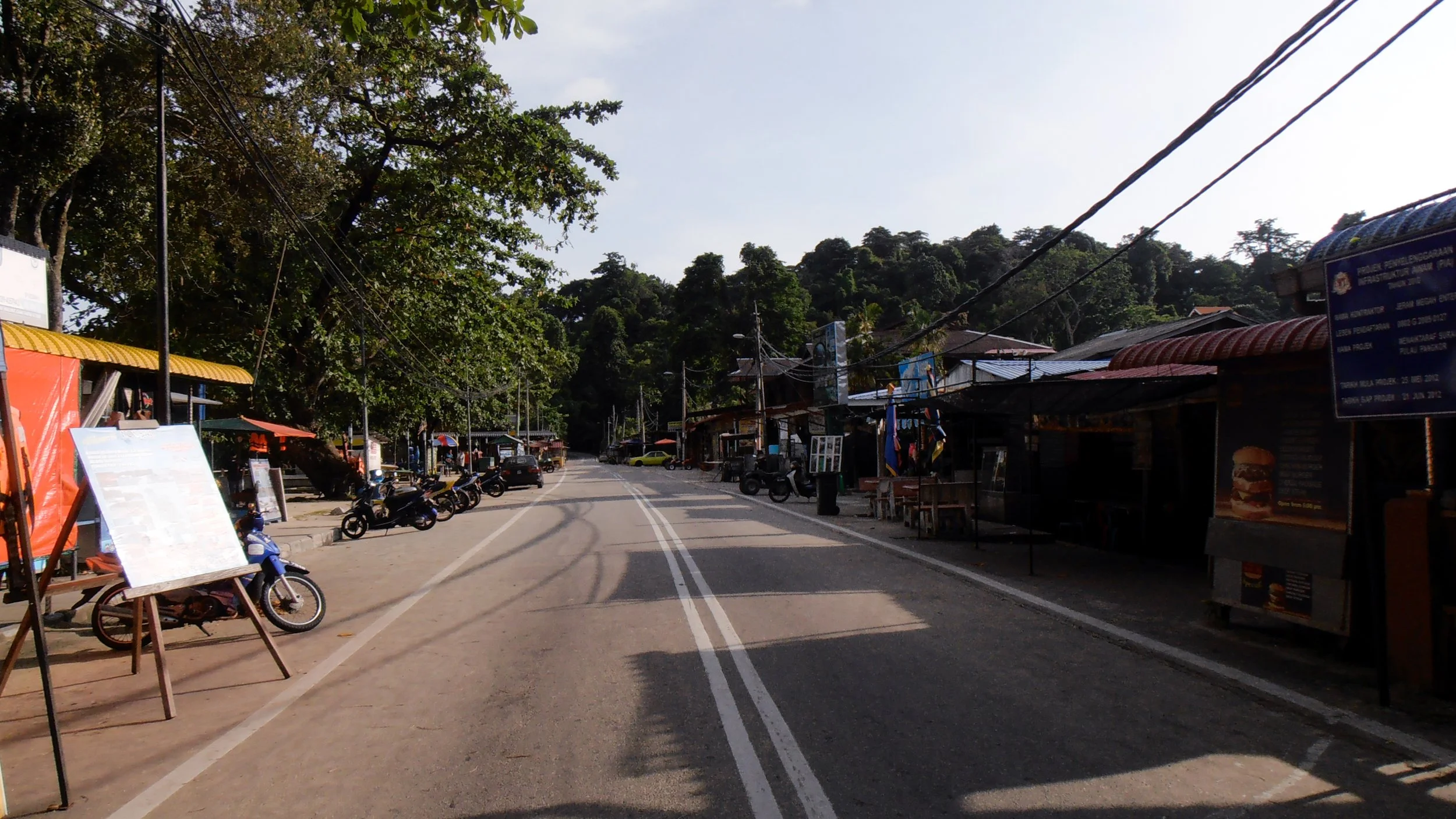 An empty road on Pangkor Island in Malaysia, lined with the shops and scooters of the locals