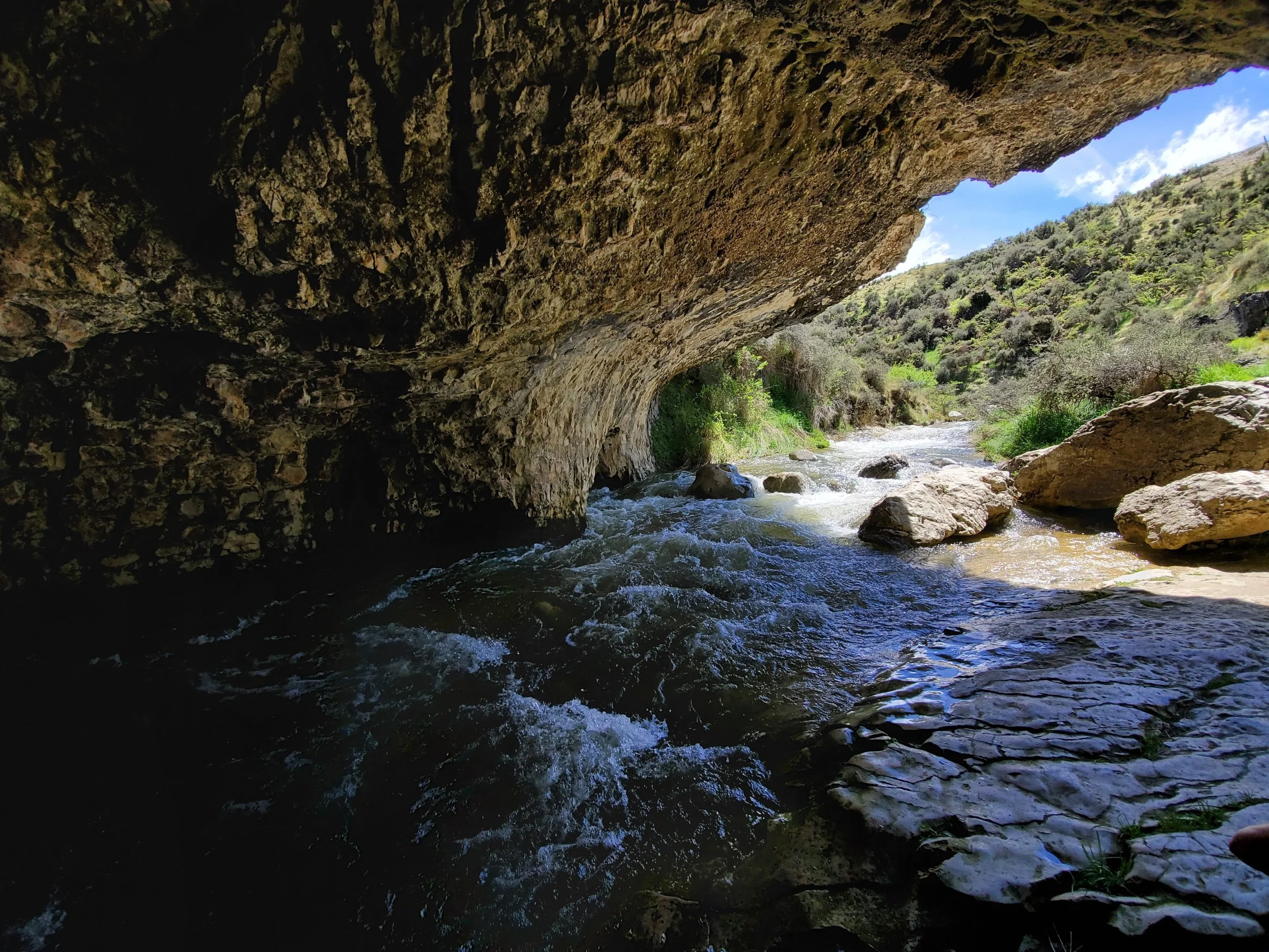 South Island's Cave stream walk view from inside one of the caves. hills are covered in small bristley shrubs