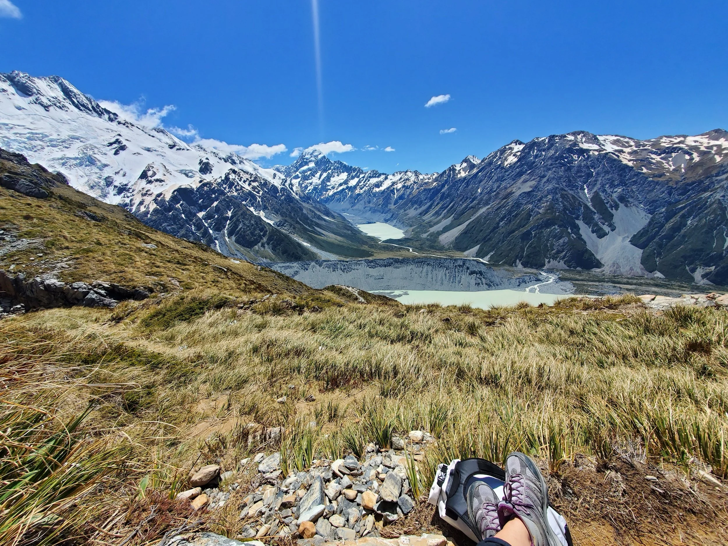 long, pale grasses, snow capped mountains, pale green alpine lakes, blue skies