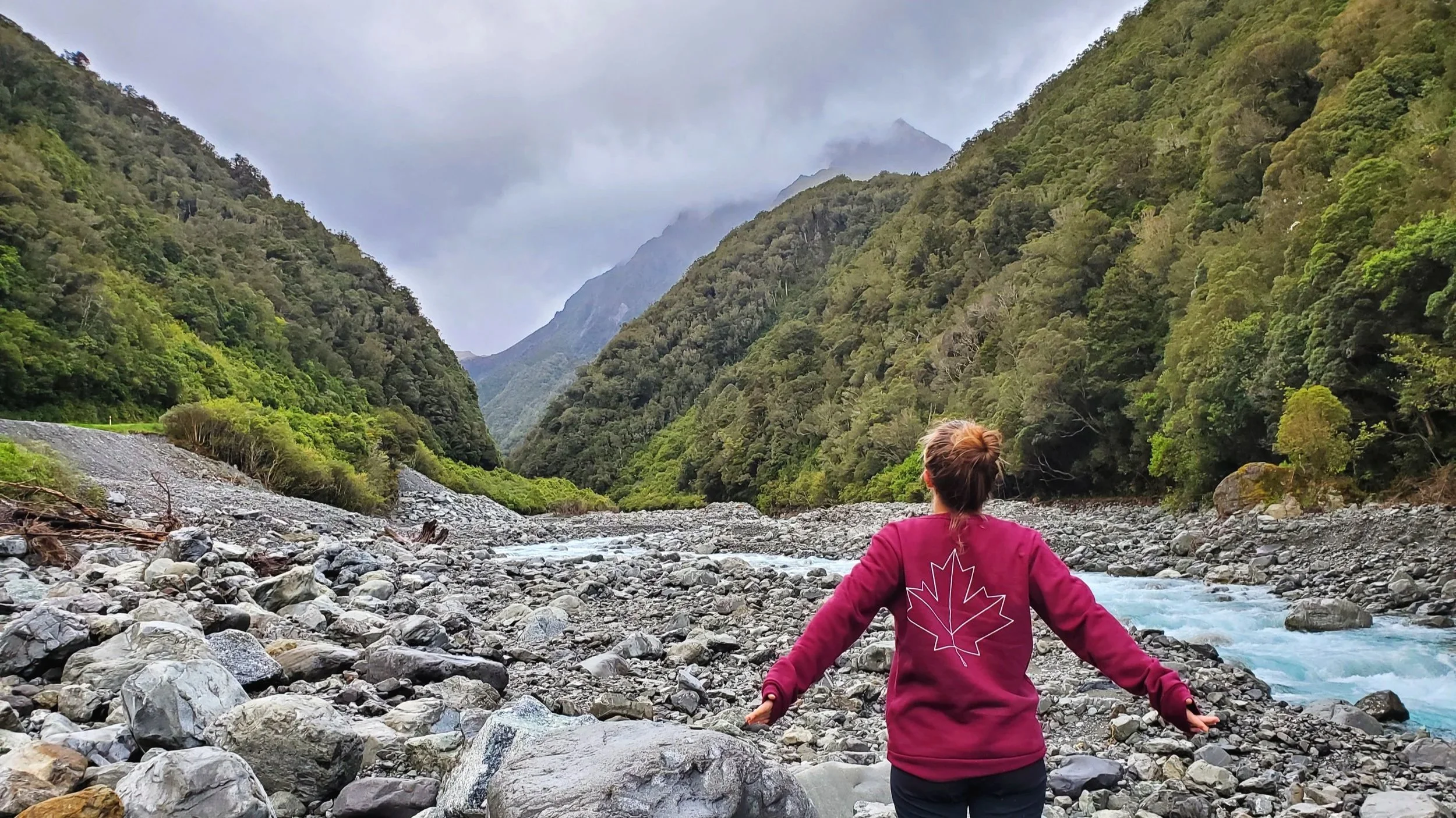 Megan looking out at the cloud covered valley bright blue river flows beside