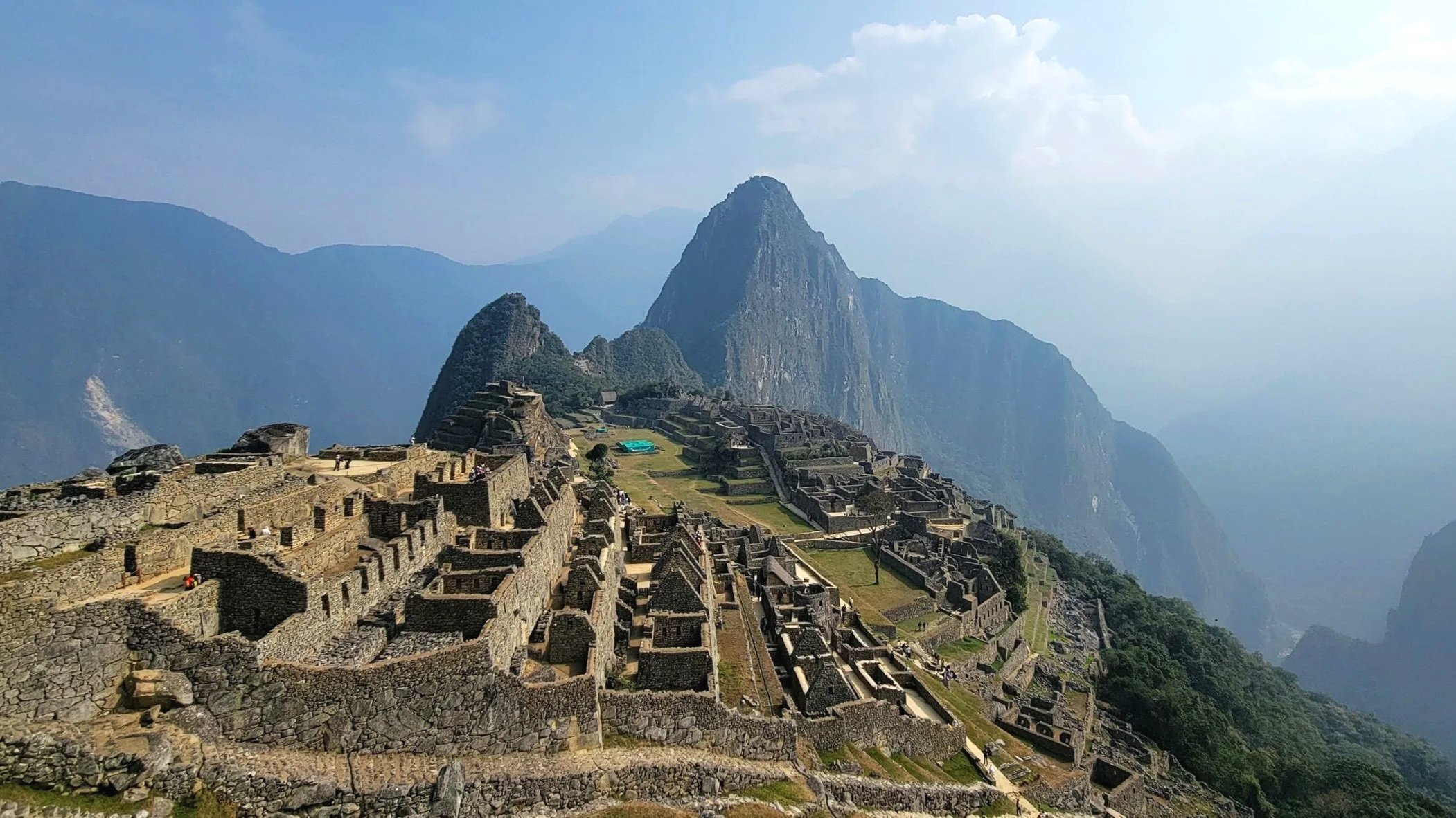 The famous view of machu picchu, with the ruins in the foreground and the peak in the distance.