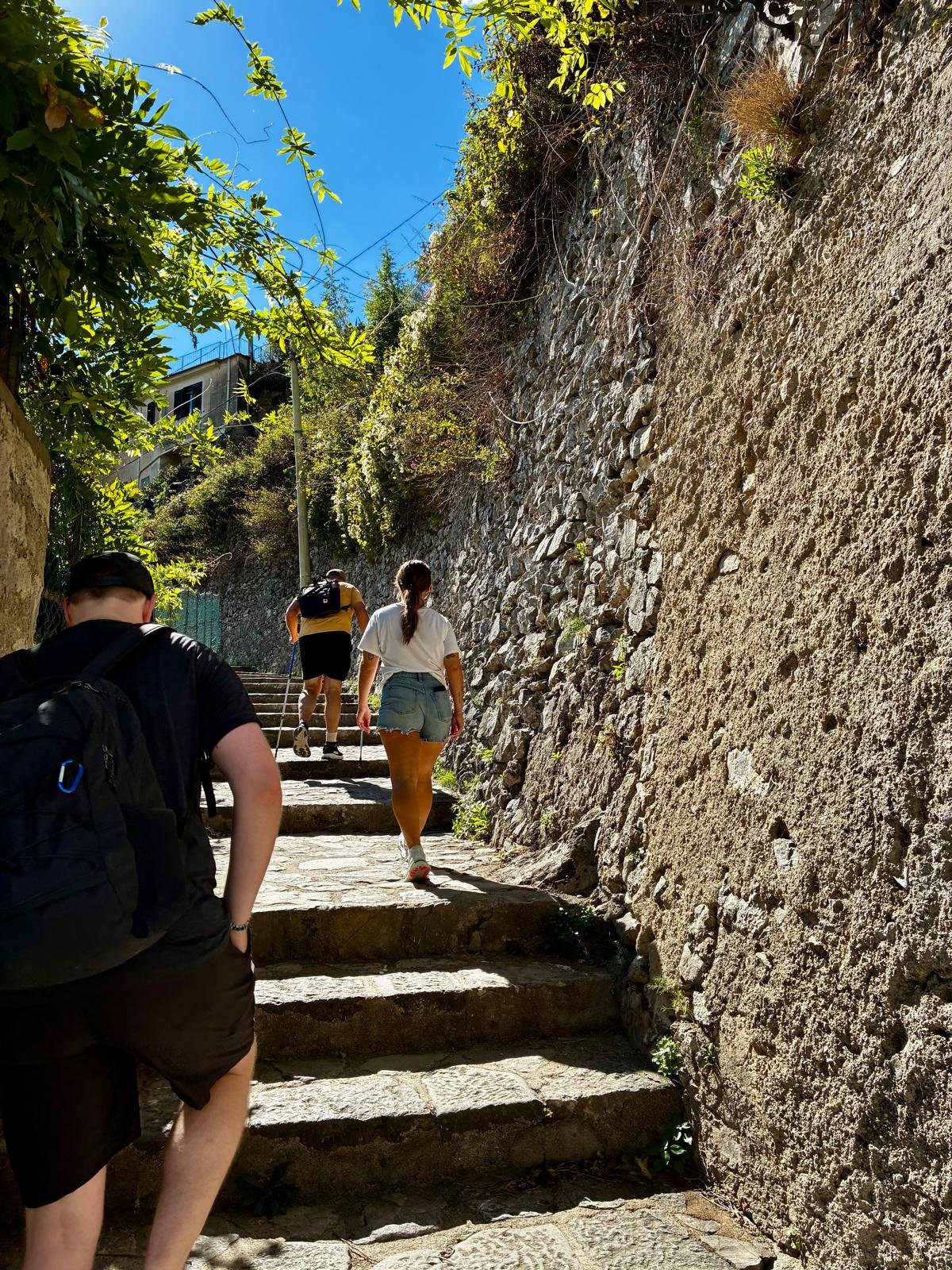 Megan and Tys walking up a set of cobblestone stairs. a walk wall on either side of the path with greenery creeping overtop