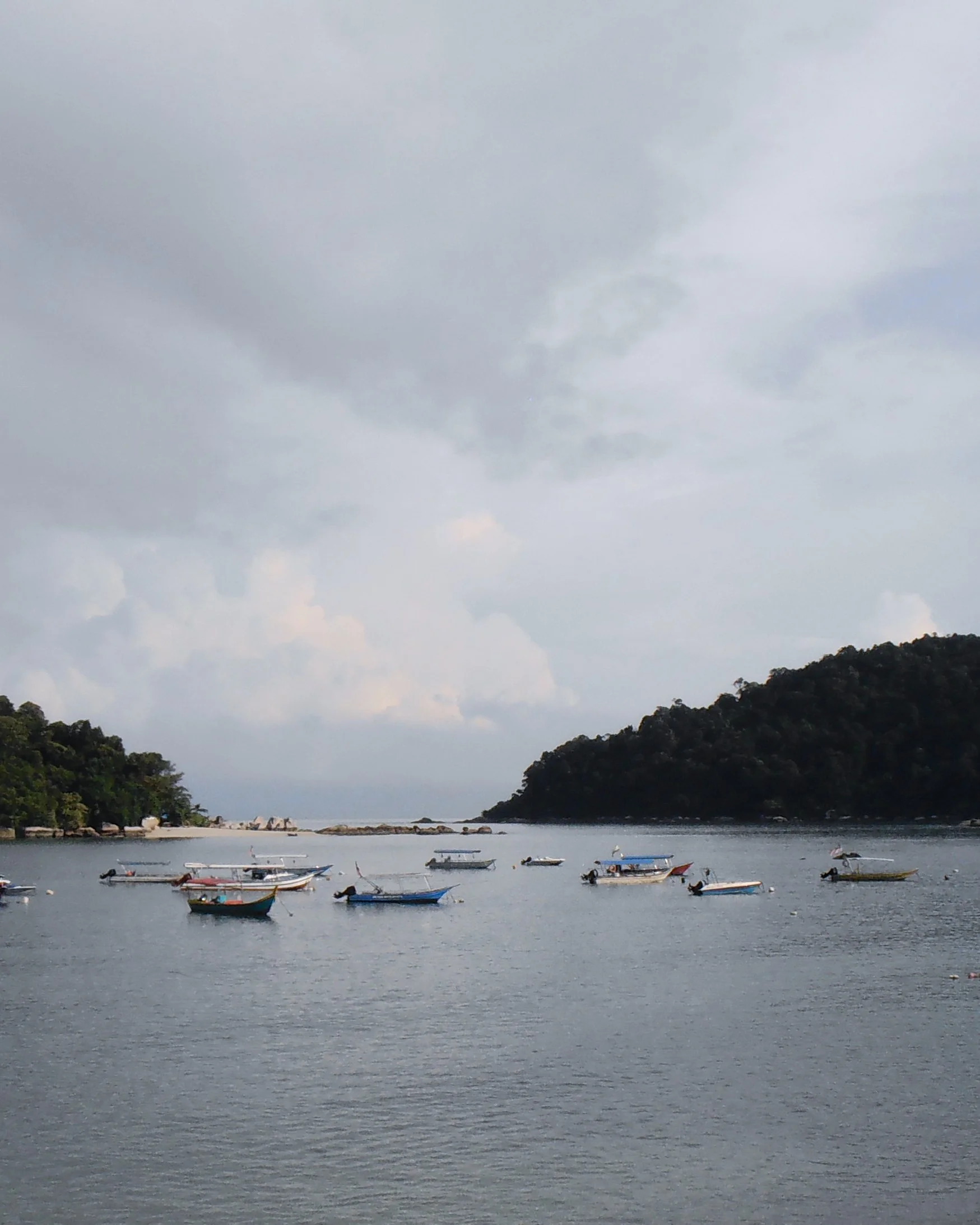 Fishing boats anchored in the bay under grey skies
