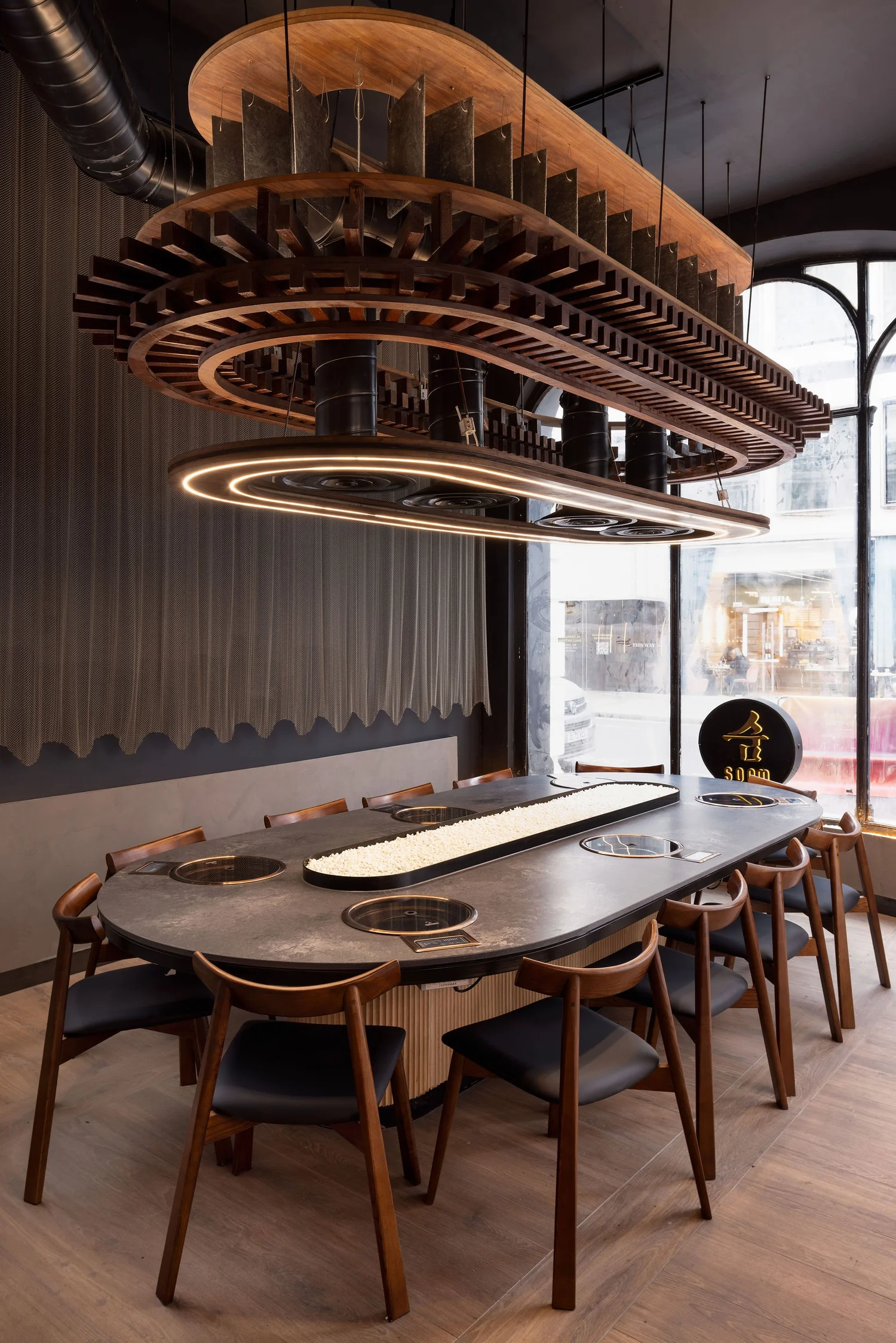 Communal dining table and suspended timber lighting at Soom