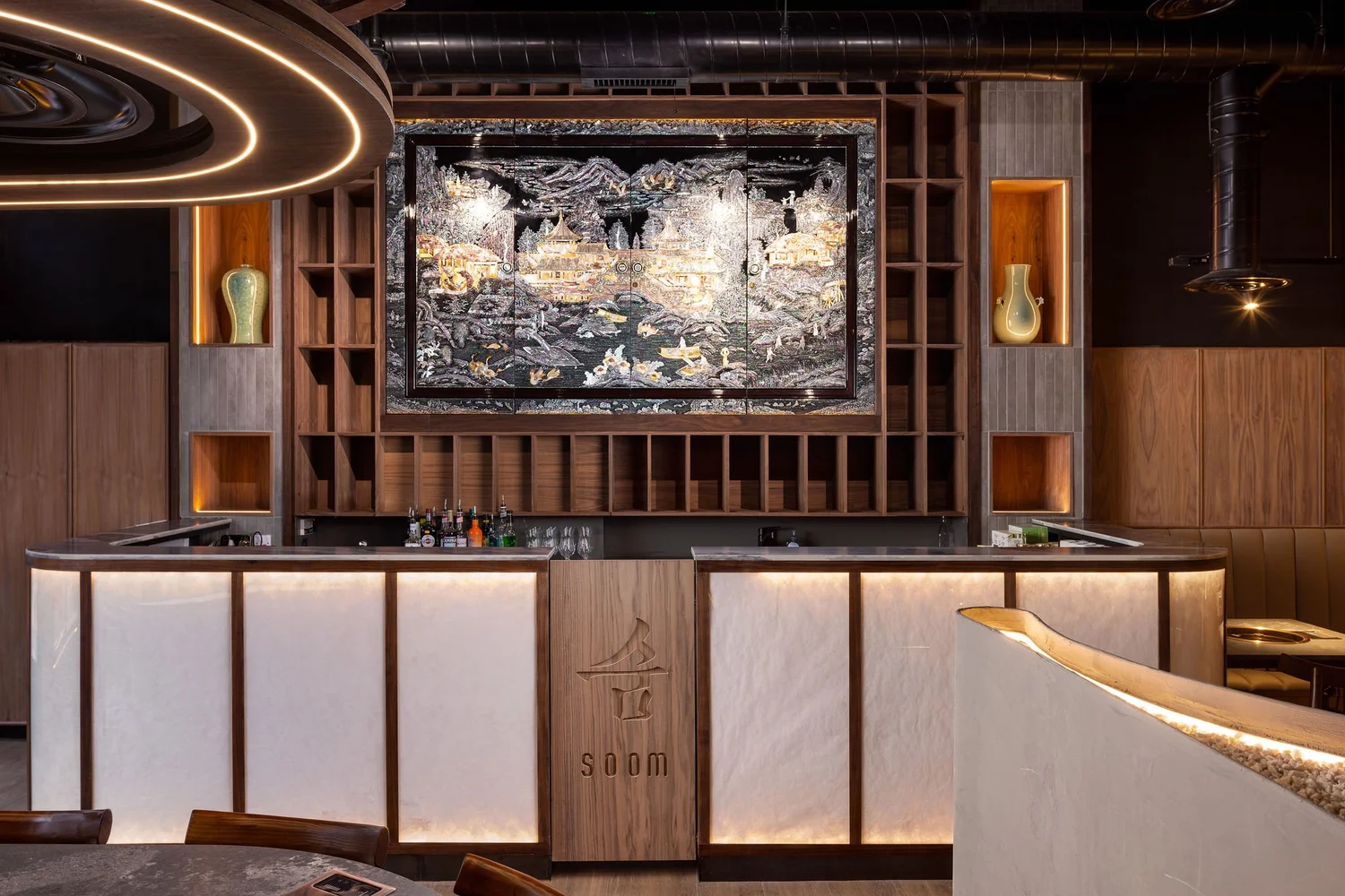 Soom bar with illuminated panels, timber shelving and a mother-of-pearl artwork above the counter.