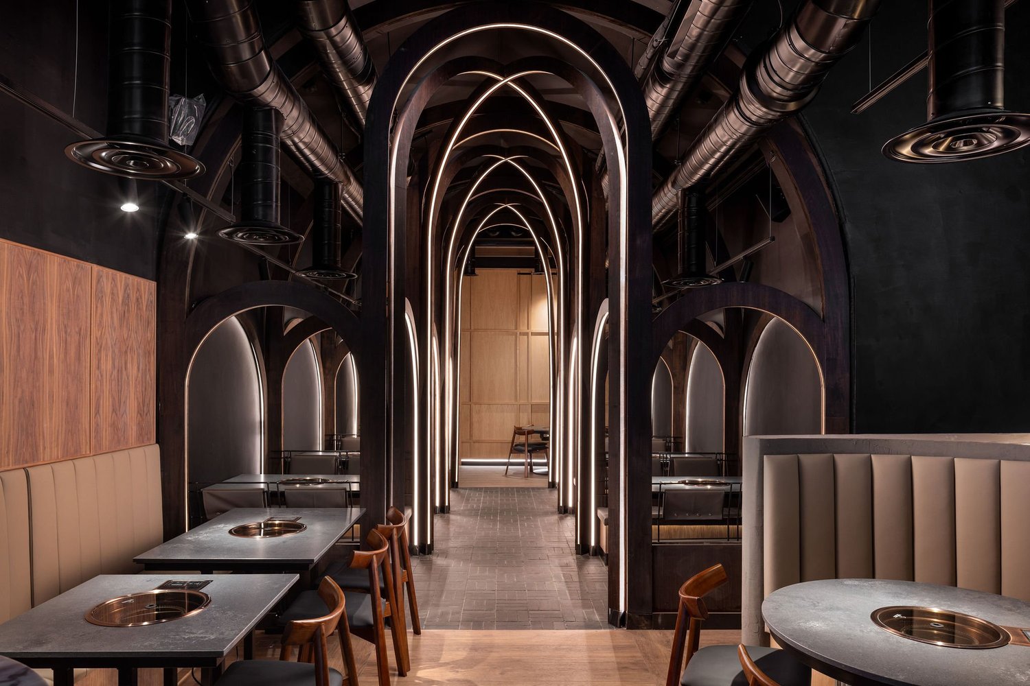 Soom restaurant interior with timber arches, illuminated curves and dining booths.