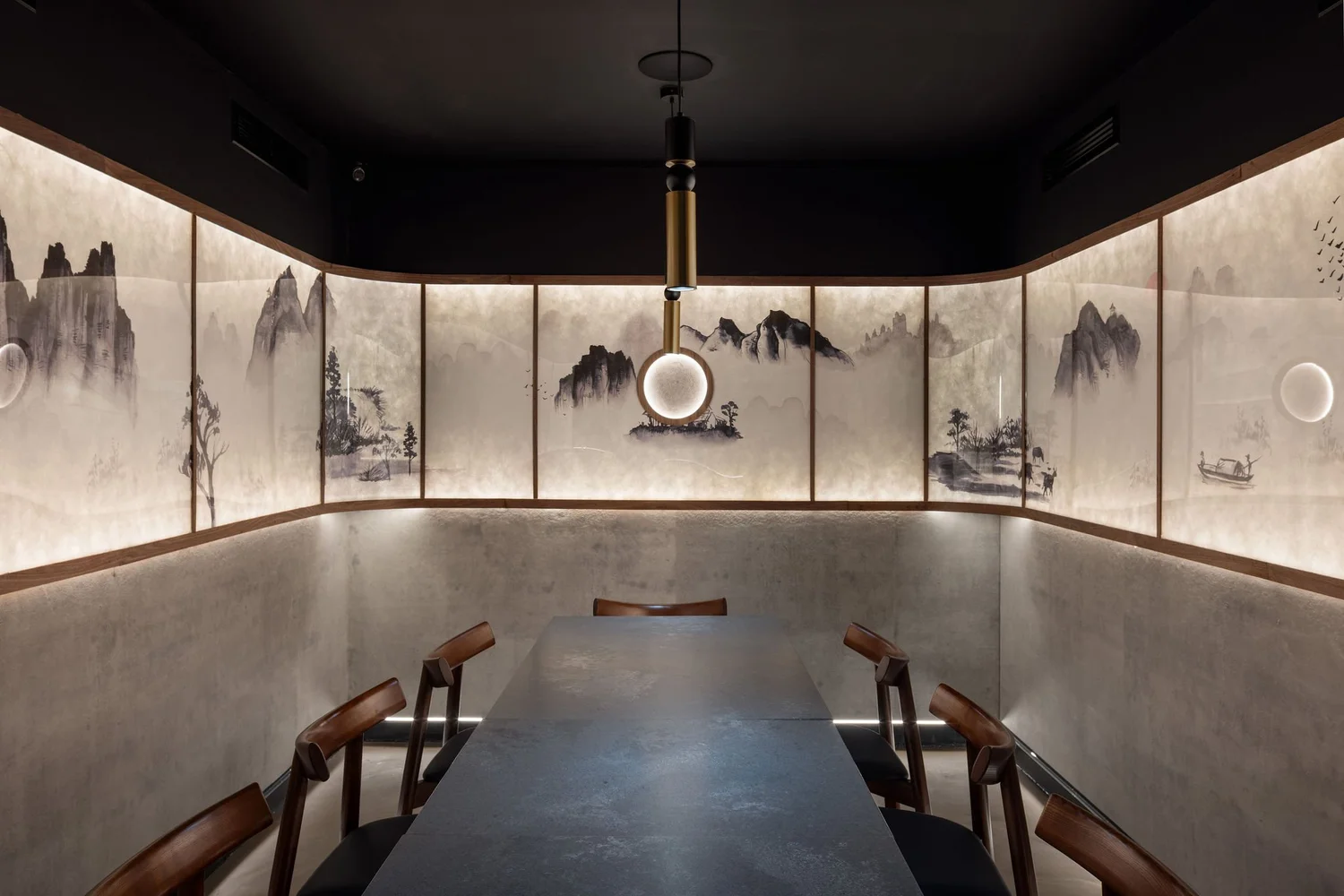 Soom private dining room with backlit landscape panels, a long table and a circular pendant light.