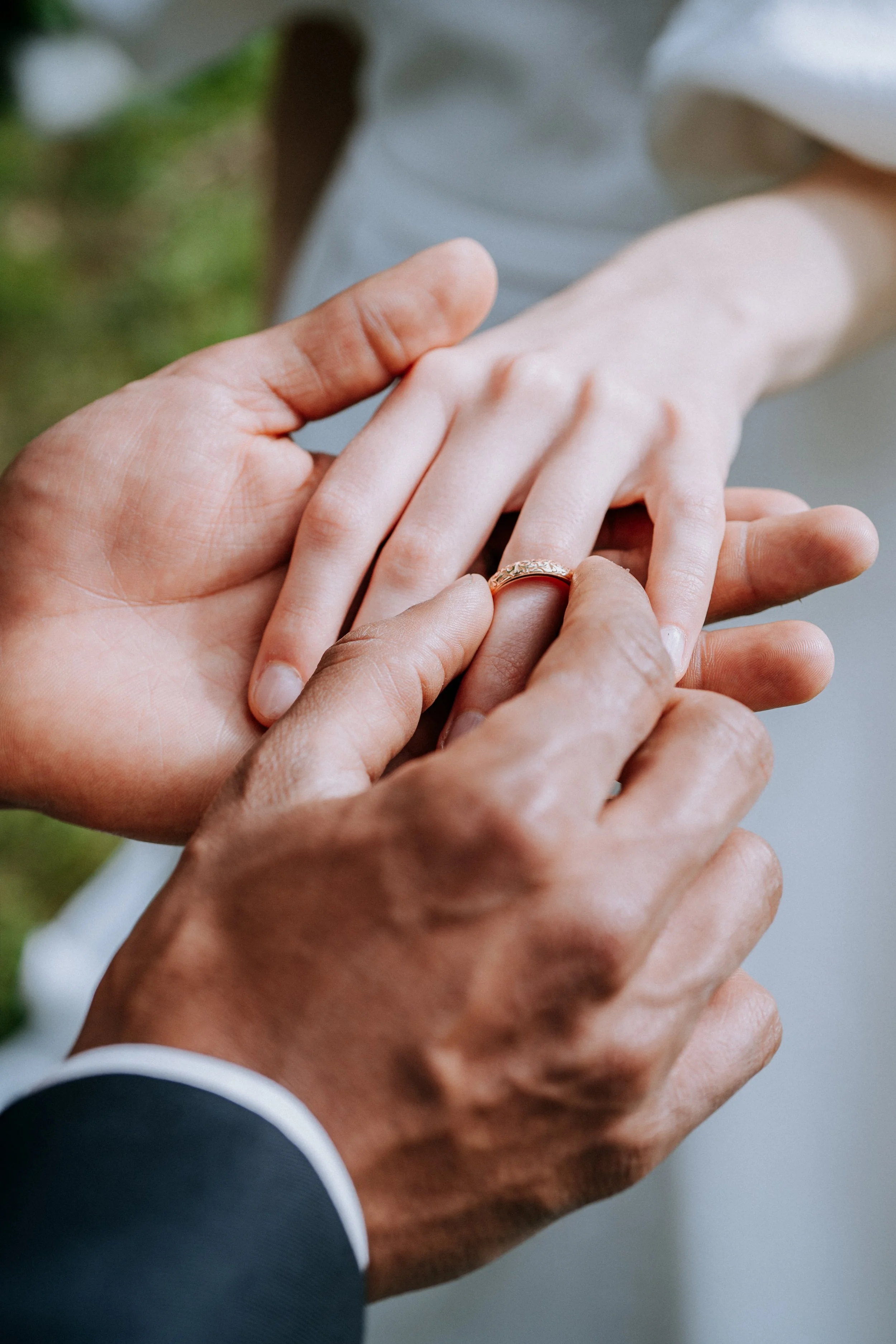 Close-up of a person placing a wedding ring on a woman's finger during a wedding ceremony.
