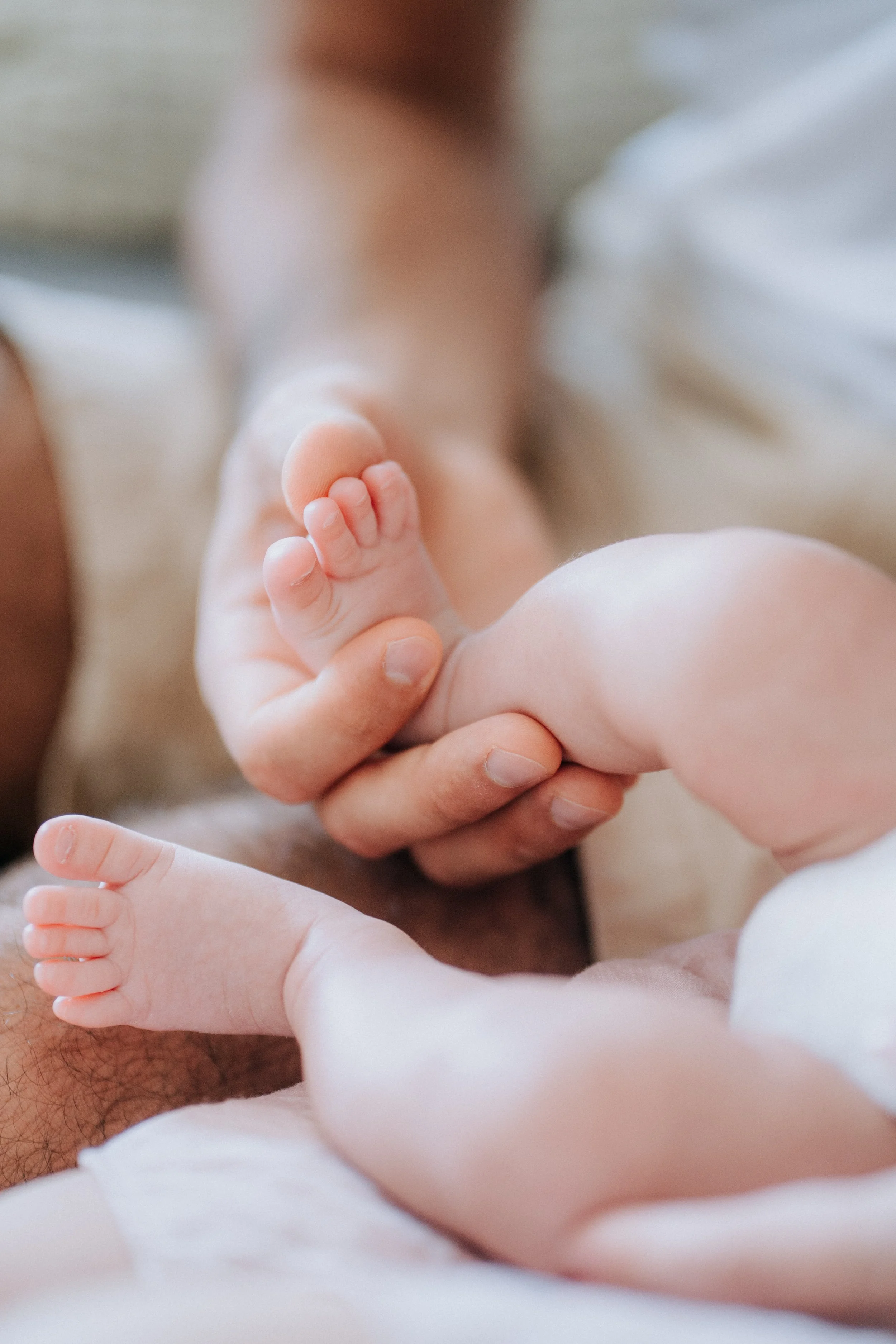 Close-up of a person's hand holding a baby's foot, showing the baby's toes.