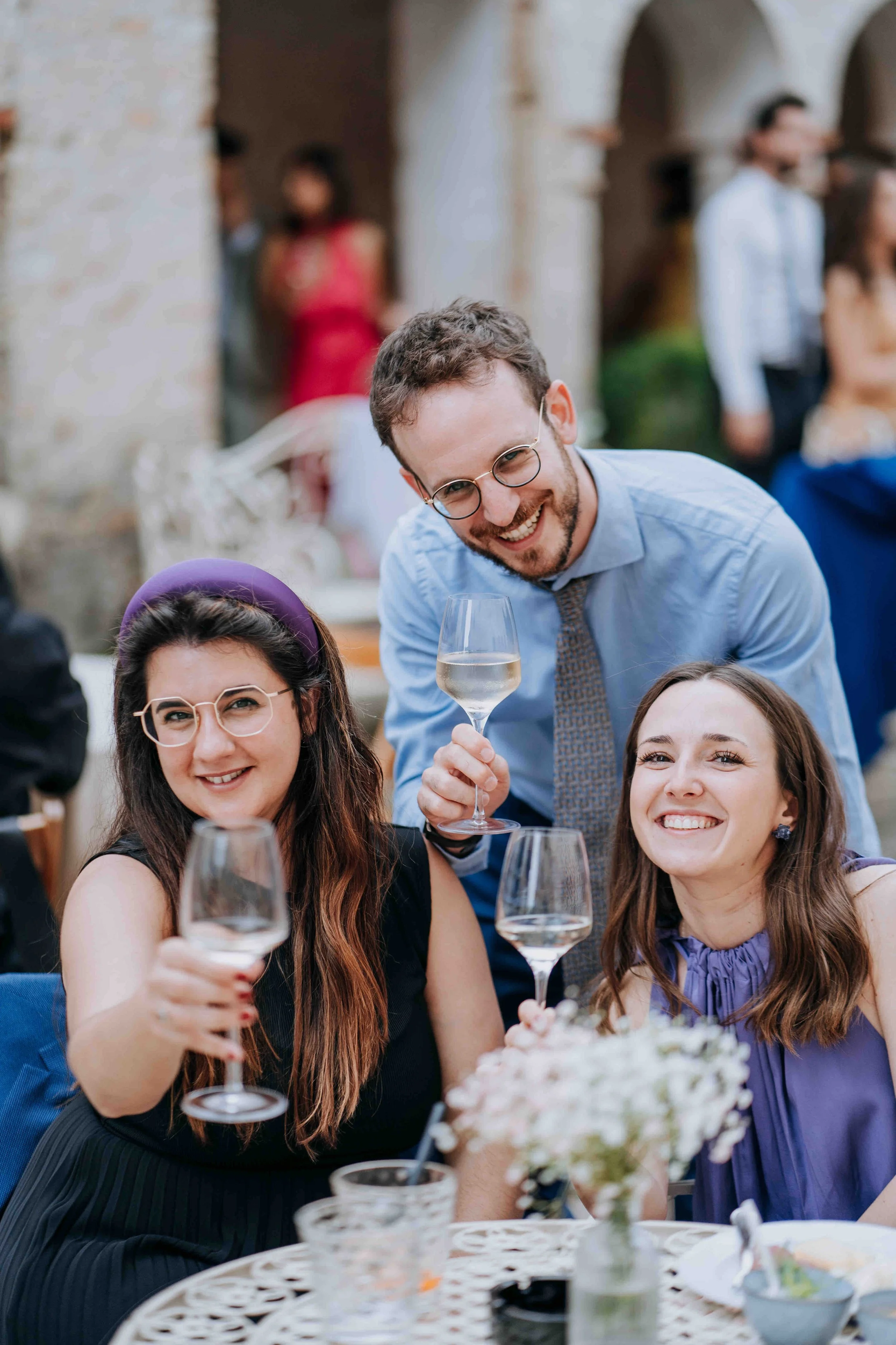 People celebrating at an outdoor event, smiling and holding wine glasses.