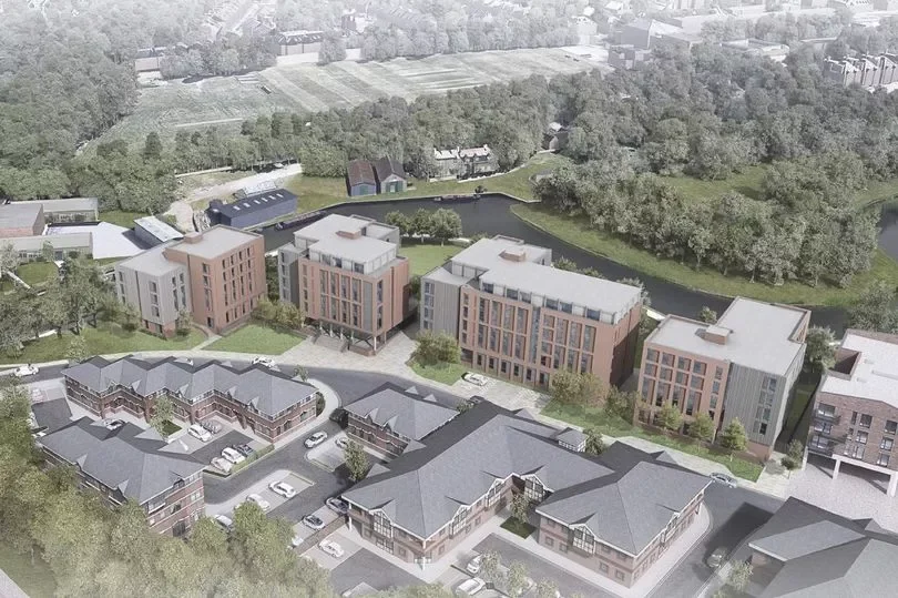 A modern residential complex with multiple mid-rise apartment buildings and townhouses surrounded by green trees and a water feature.