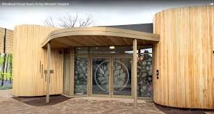 Modern building with curved wooden exterior and glass entrance doors.