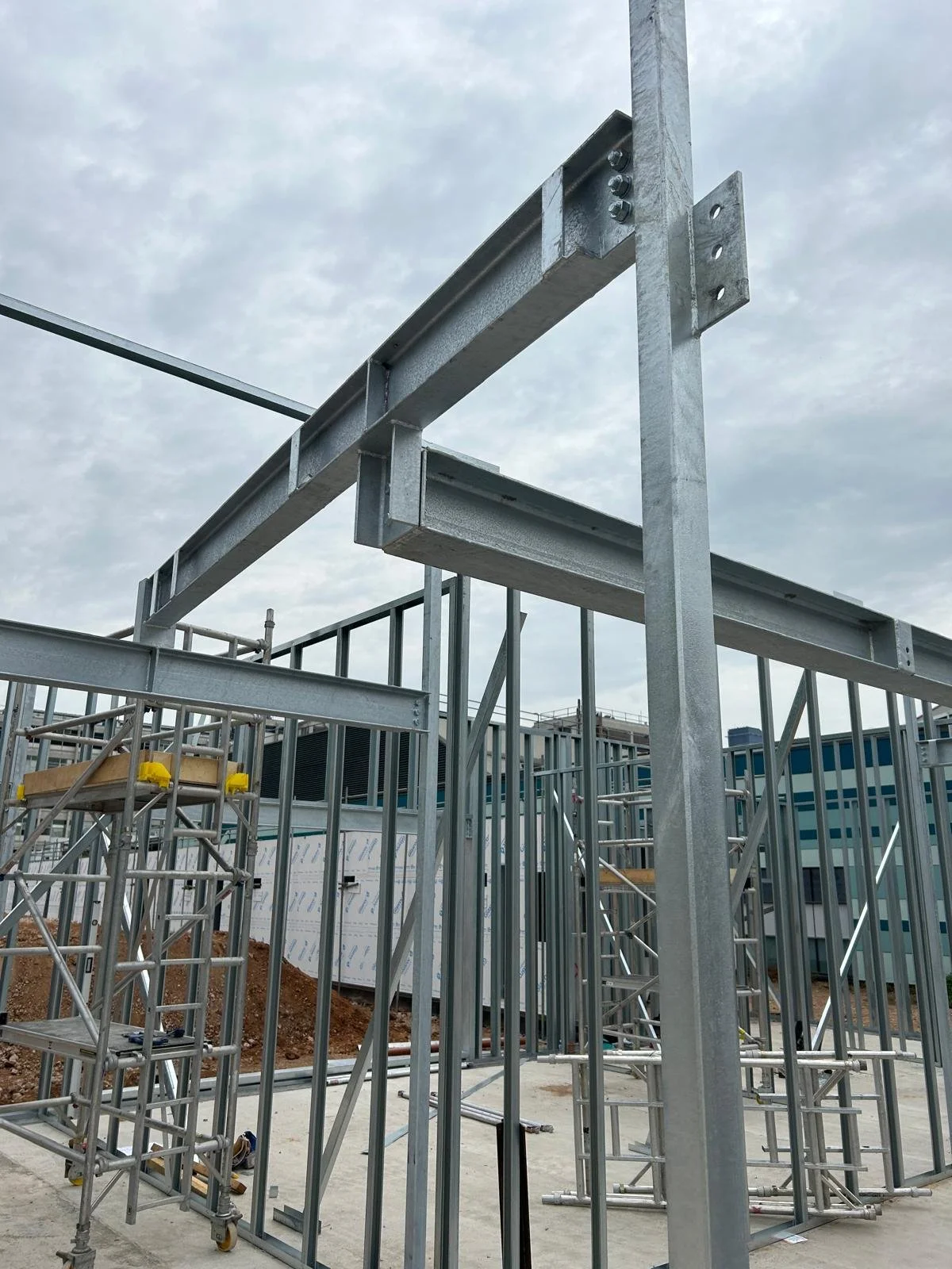 Metal framework and scaffolding at a construction site with a cloudy sky in the background.