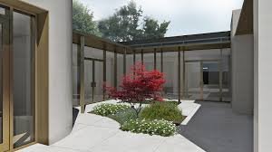 Courtyard with a central red-leafed tree, surrounded by white gravel and green plants, enclosed by modern wooden and glass walls.