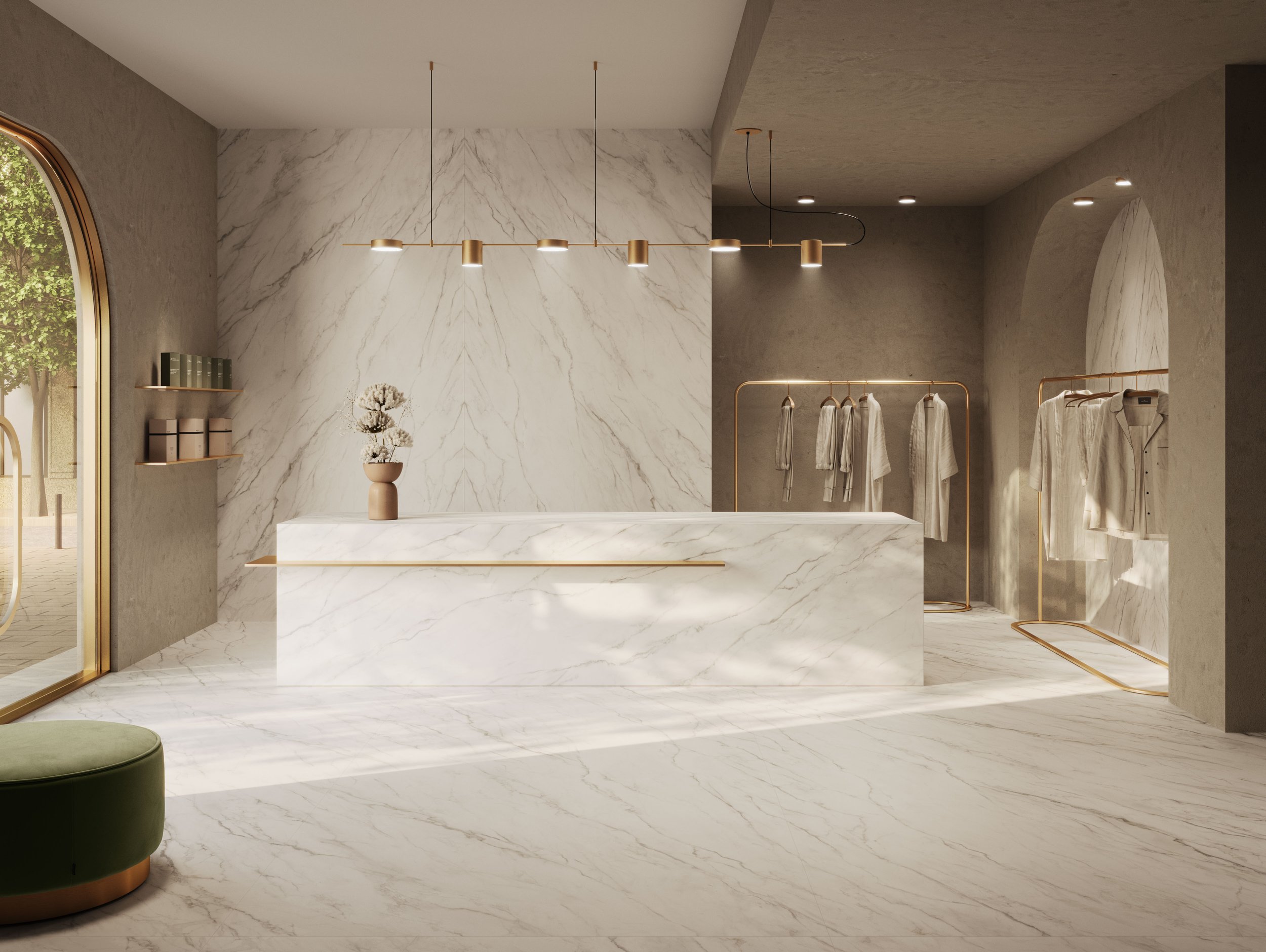 Minimalist clothing boutique with marble surfaces and brass accents, featuring hanging white garments and a vase with dried flowers on the cash register.