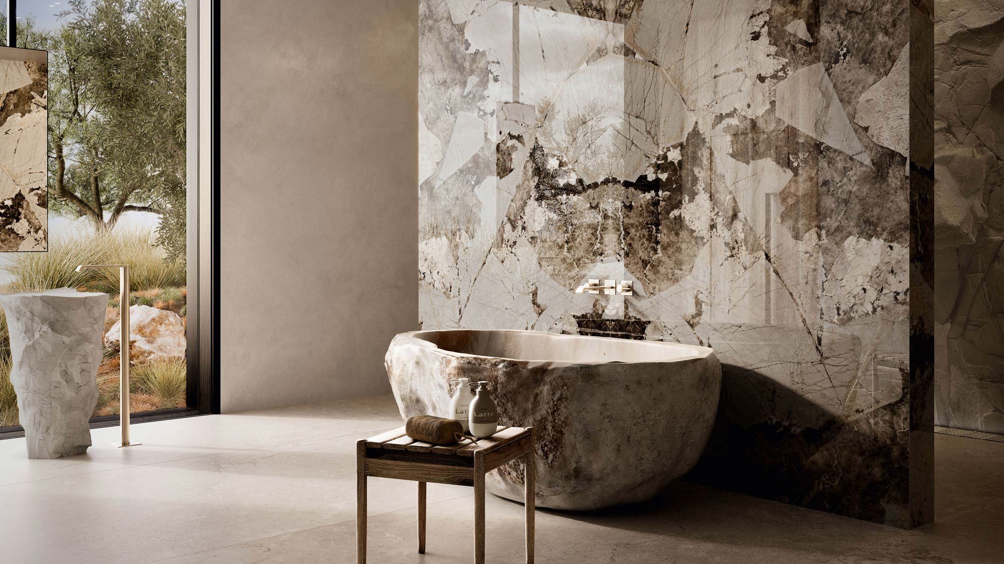 Luxury bathroom with a large stone bathtub, a marble accent wall, a small wooden table with toiletries, and an outdoor view through glass doors showing trees and rocks.
