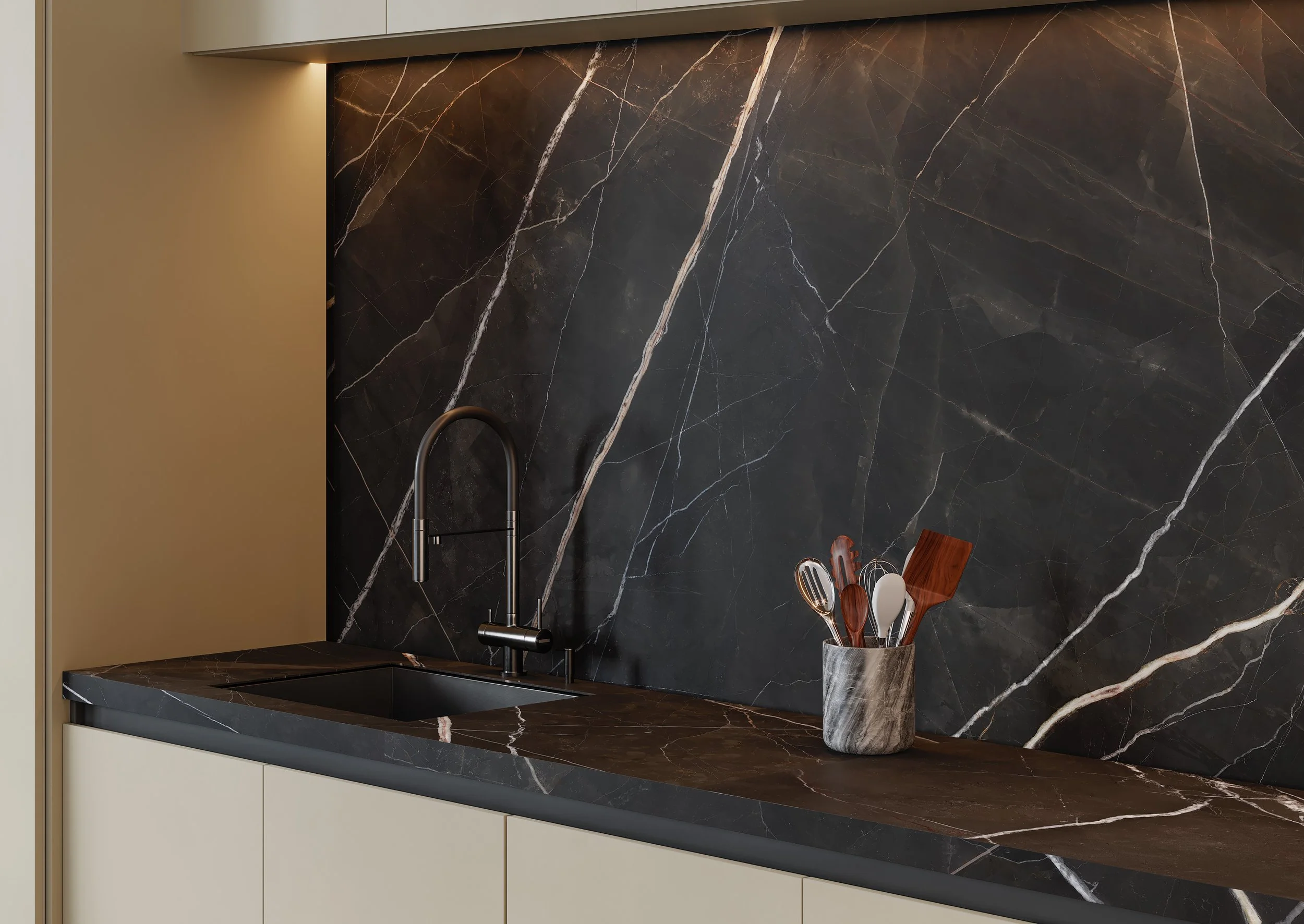 Modern kitchen countertop with black marble backsplash, a black faucet, and a marble utensil holder containing various cooking tools.
