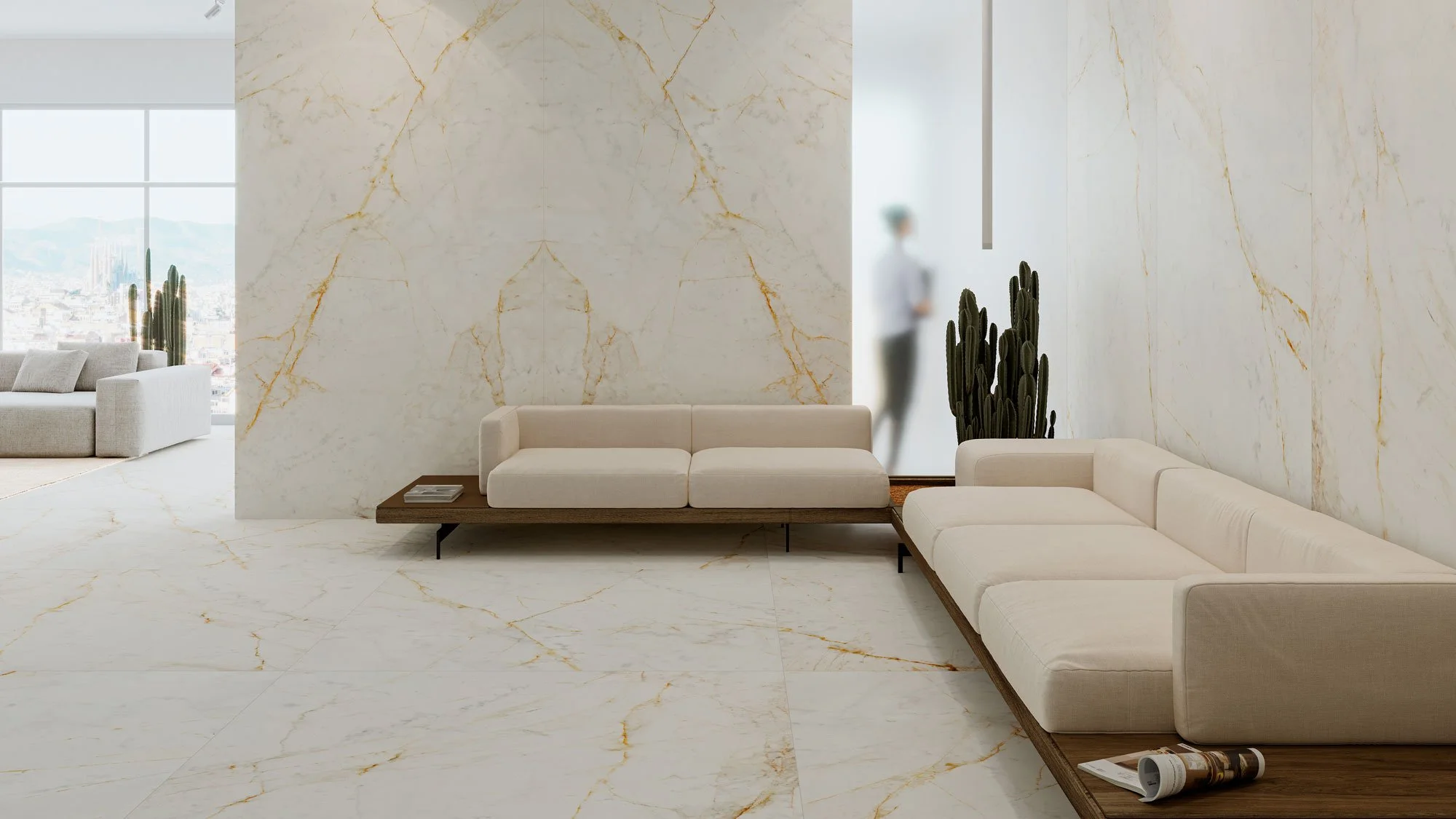 Modern living room with white marble walls and flooring, beige sofas, a cactus plant, and a blurred person standing near a window.