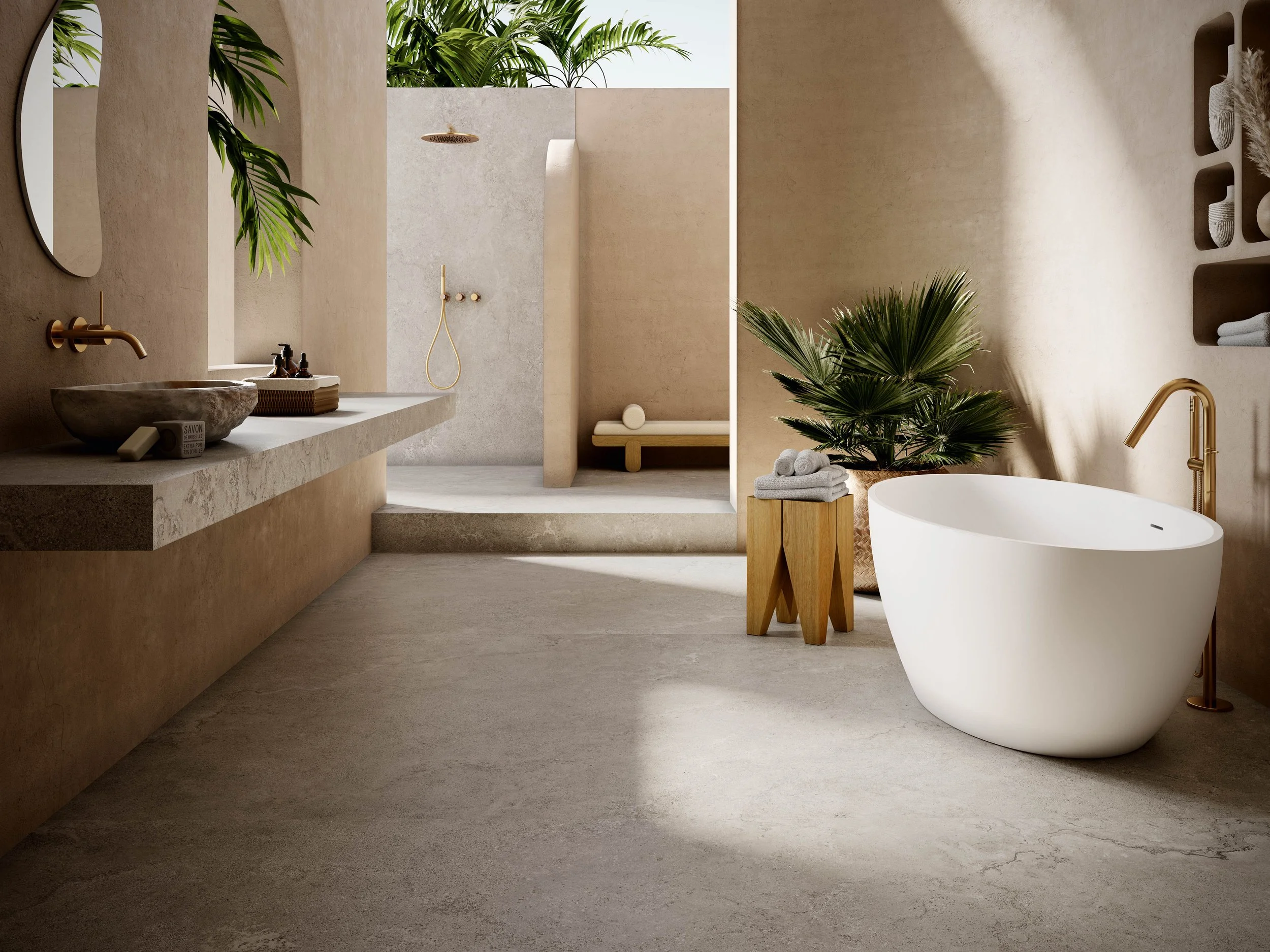 Modern bathroom with a white bathtub, wooden side table with rolled towels, green plants, beige walls, and a walk-in shower in the background with a gold showerhead and fixtures.