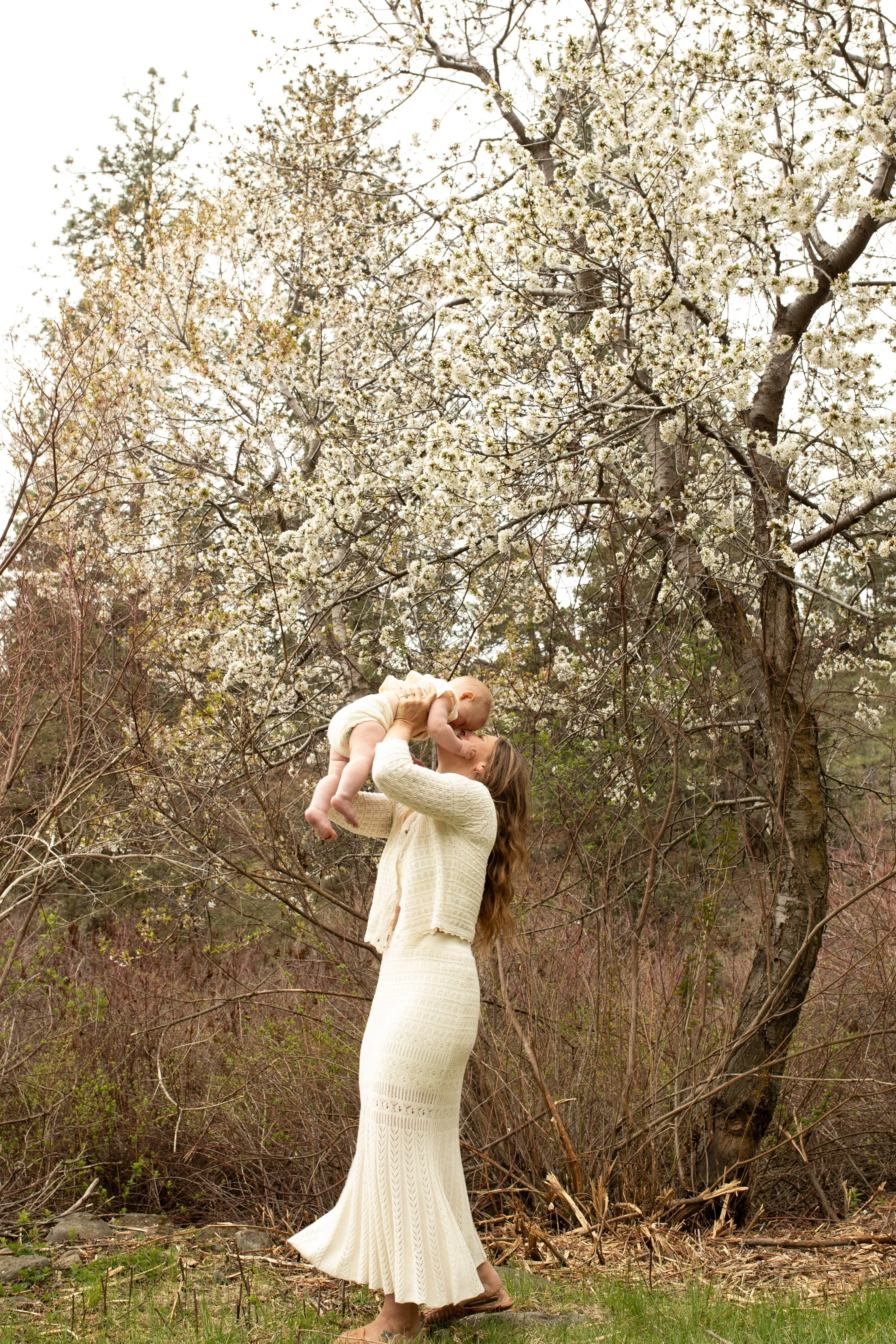 Mother and baby in nature dressed in neutral tones.