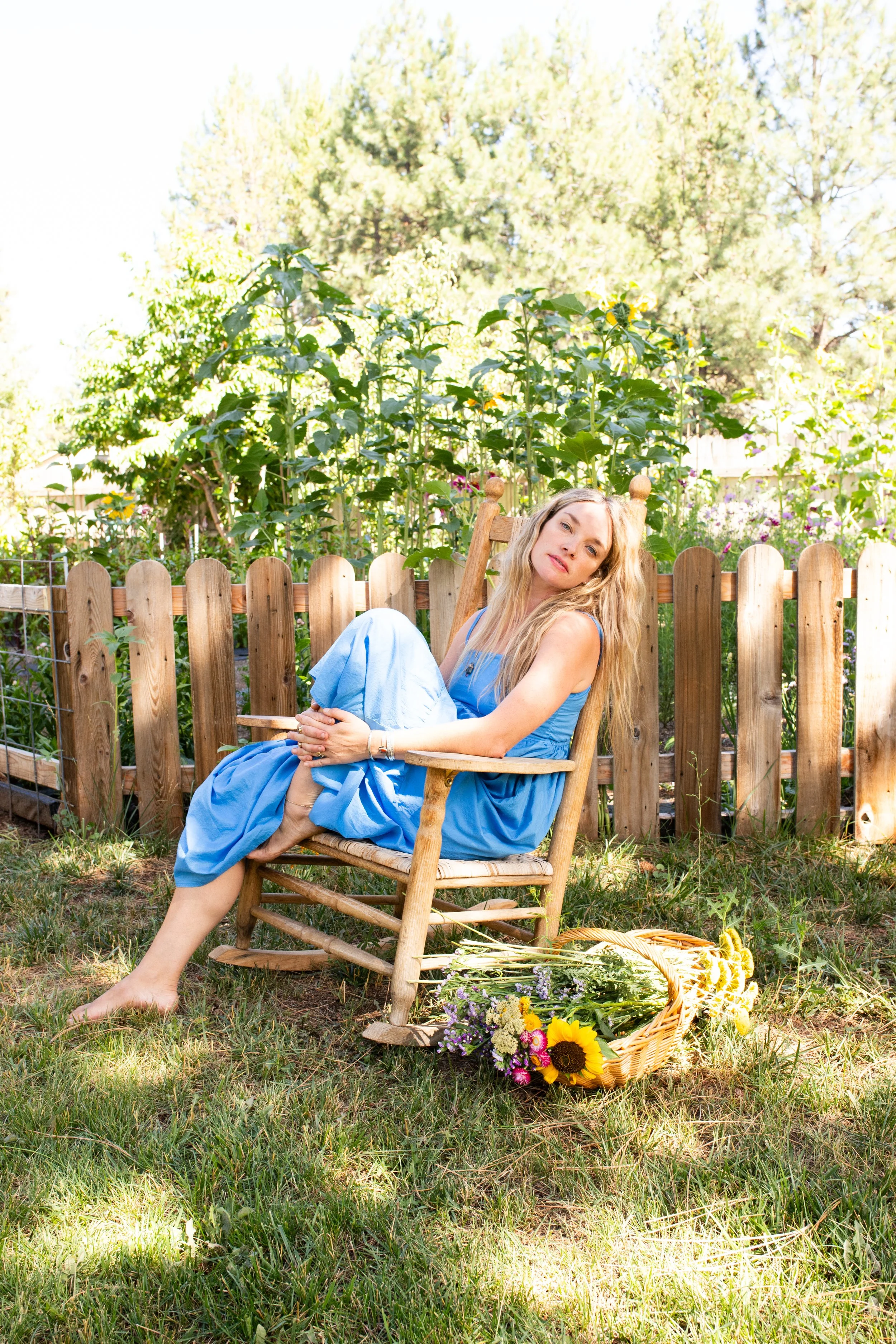 Overhead view of a meal including a colorful salad with radishes and chickpeas, a roasted chicken with lemon, a breaded dish, and various drinks, with two hands holding forks over the salad.