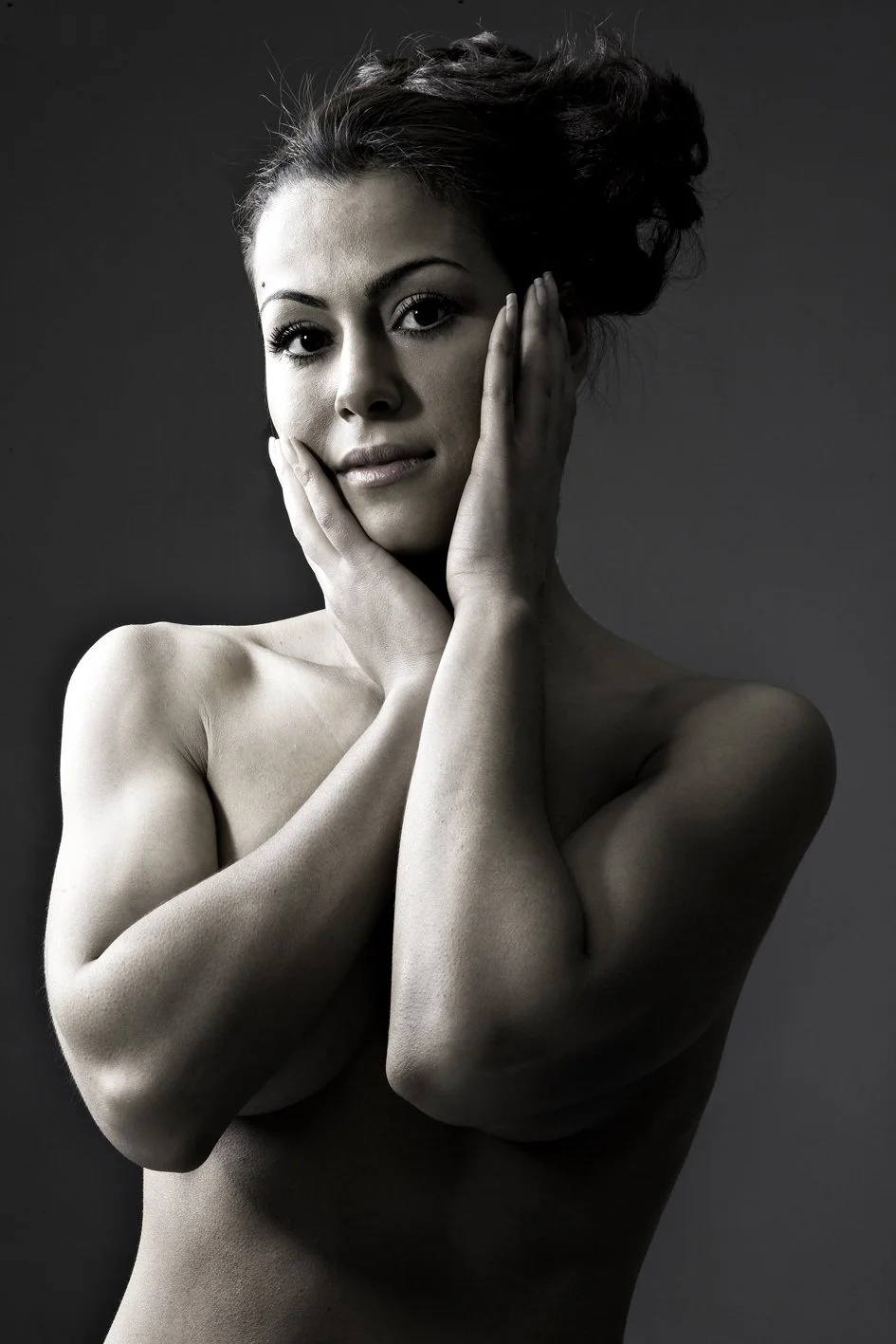 Sort-hvidt portræt af en topløs kvinde med mørkt, opskyllet hår, der rører hendes ansigt.