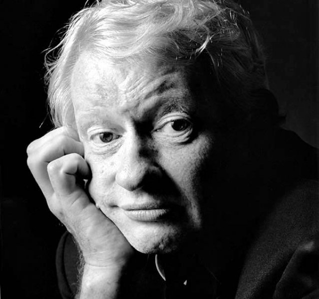 Sort-hvid portrætfoto af en ældre mand med blond hår, der hviler sit hoved på sin hånd og kigger mod kameraet.