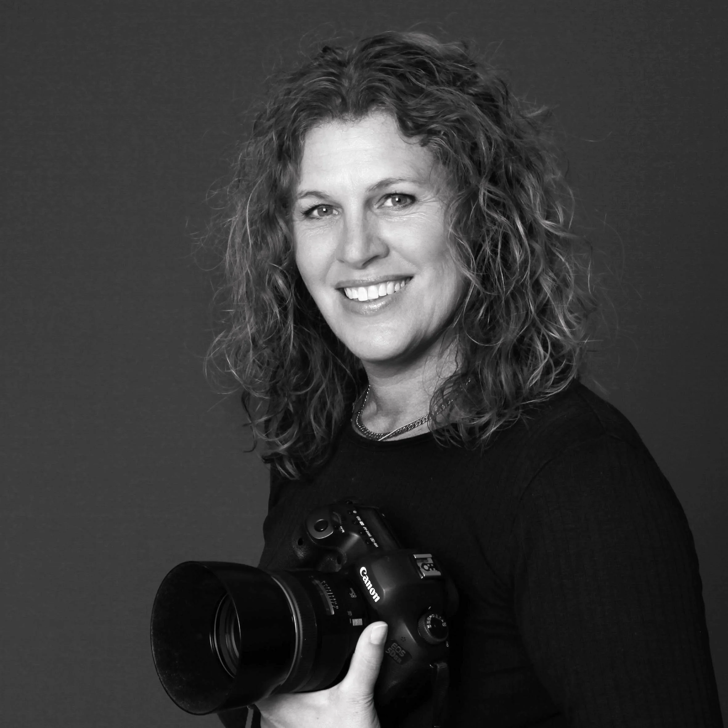 Sort-hvidt portræt af fotograf Liselotte Plenov der holder et kamera i hånden.