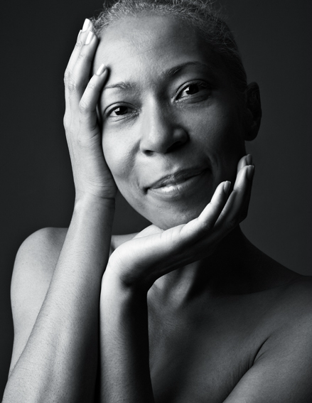 Sort-hvid portrætfotografi af en kvinde med hænderne ved ansigtet.