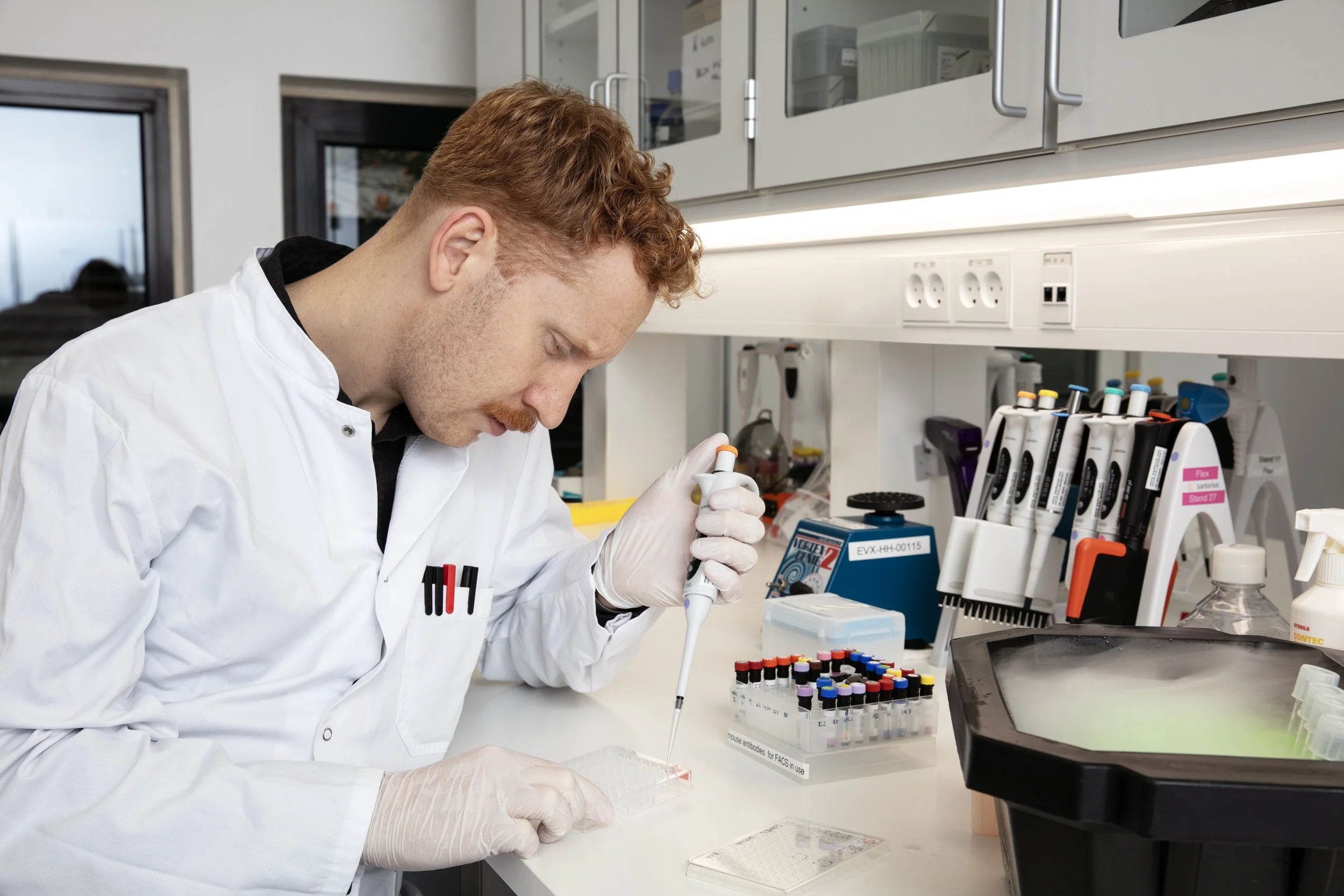 En mand i laboratorieudstyr, der arbejder med testrør og laboratorieudstyr.