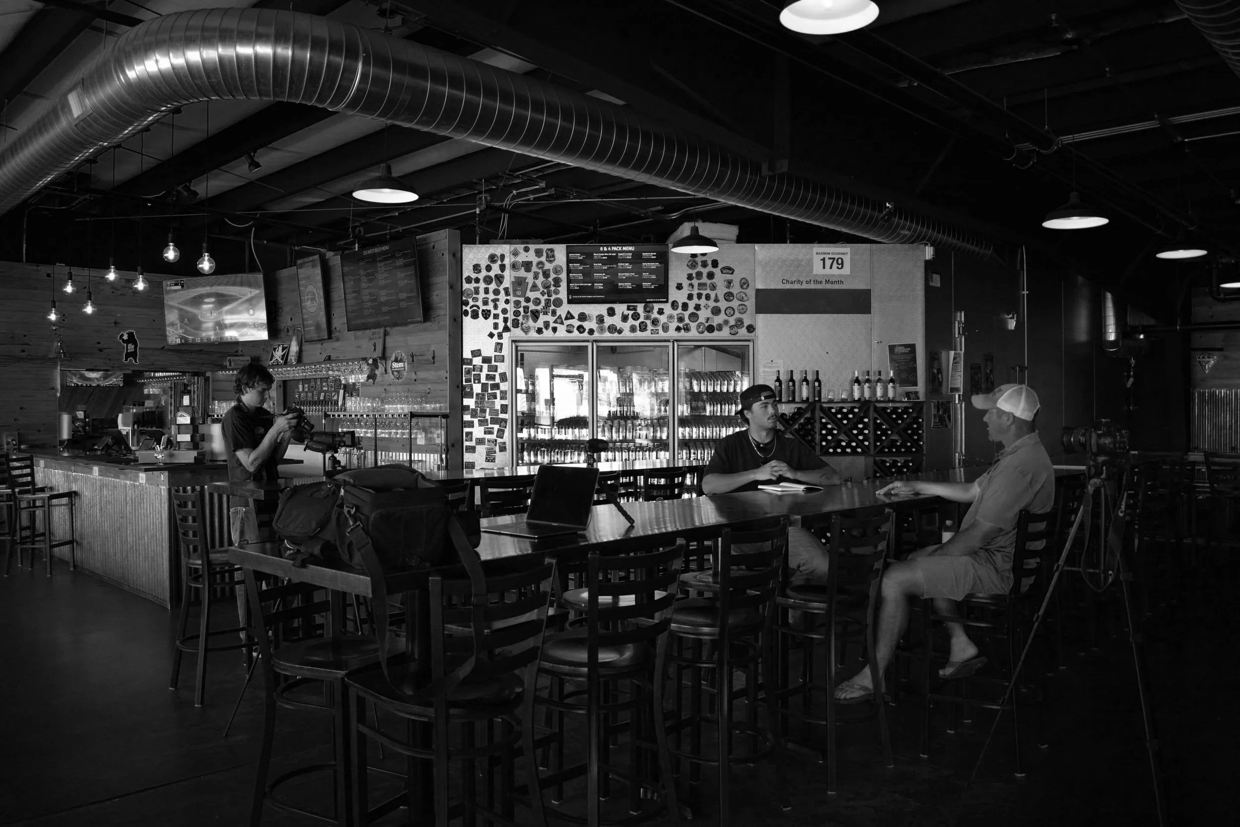 Black and white photo of snow-capped mountains with a forest of trees in the foreground.