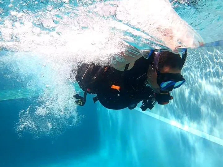 Person scuba diving underwater with diving gear and a mask.