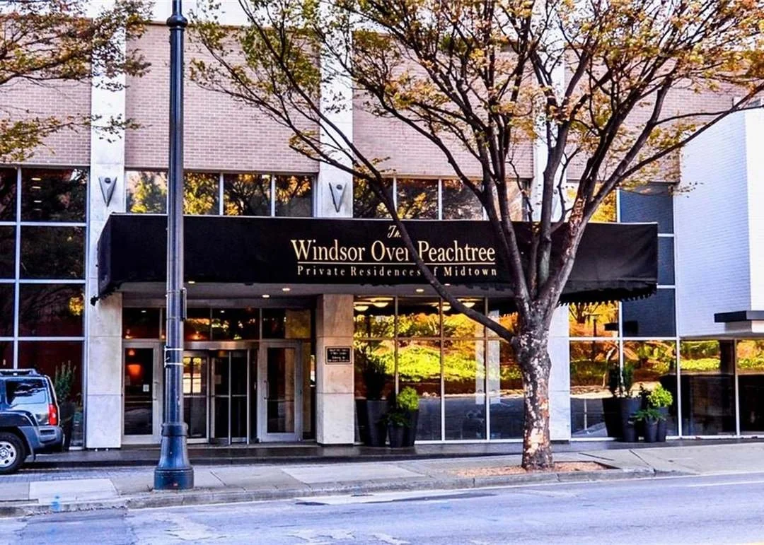 Exterior of Windsor Over Peachtree private residence building with black awning, glass windows, and a tree in front.